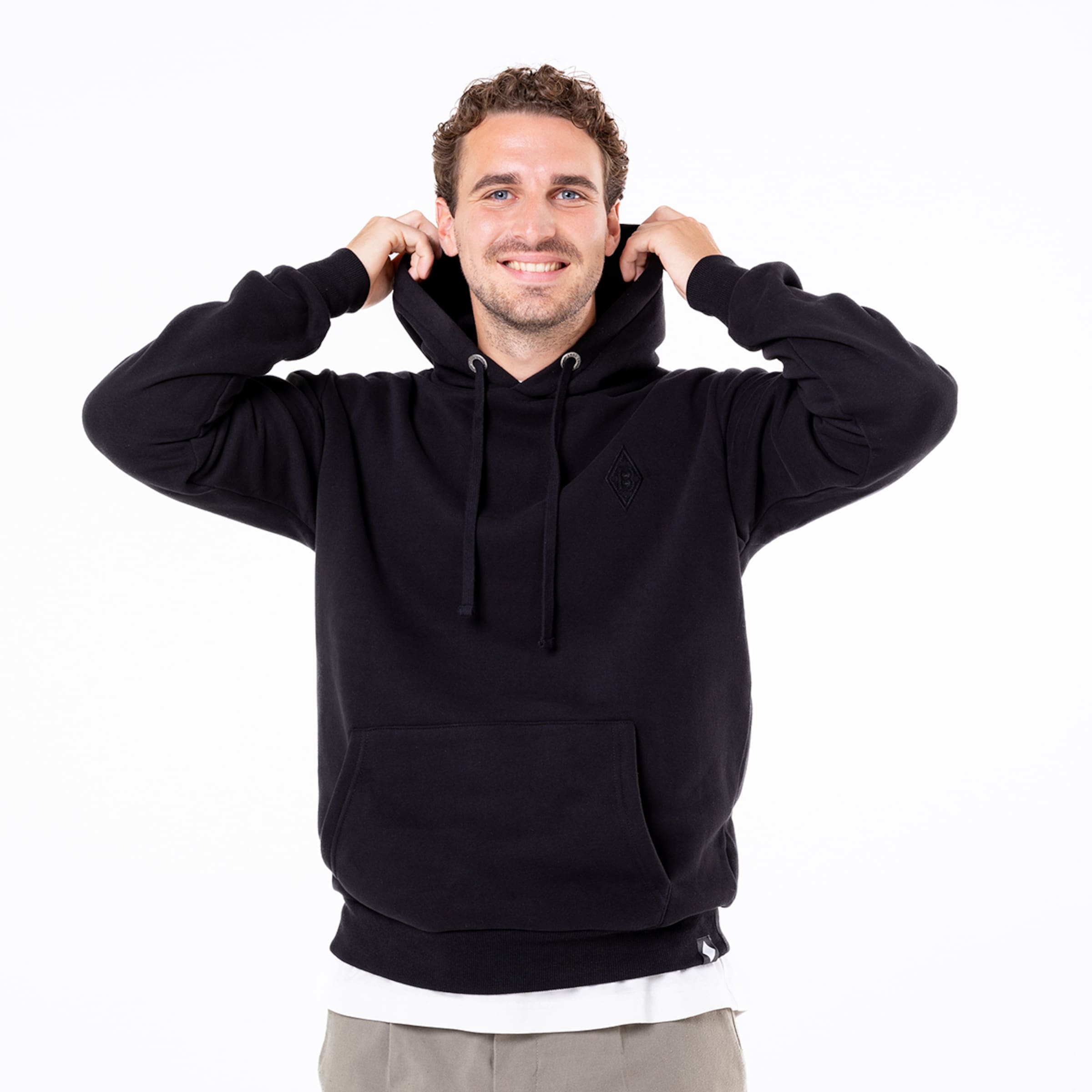 Mann mit lächelndem Gesicht trägt schwarzen Kapuzenpullover mit Taschen.