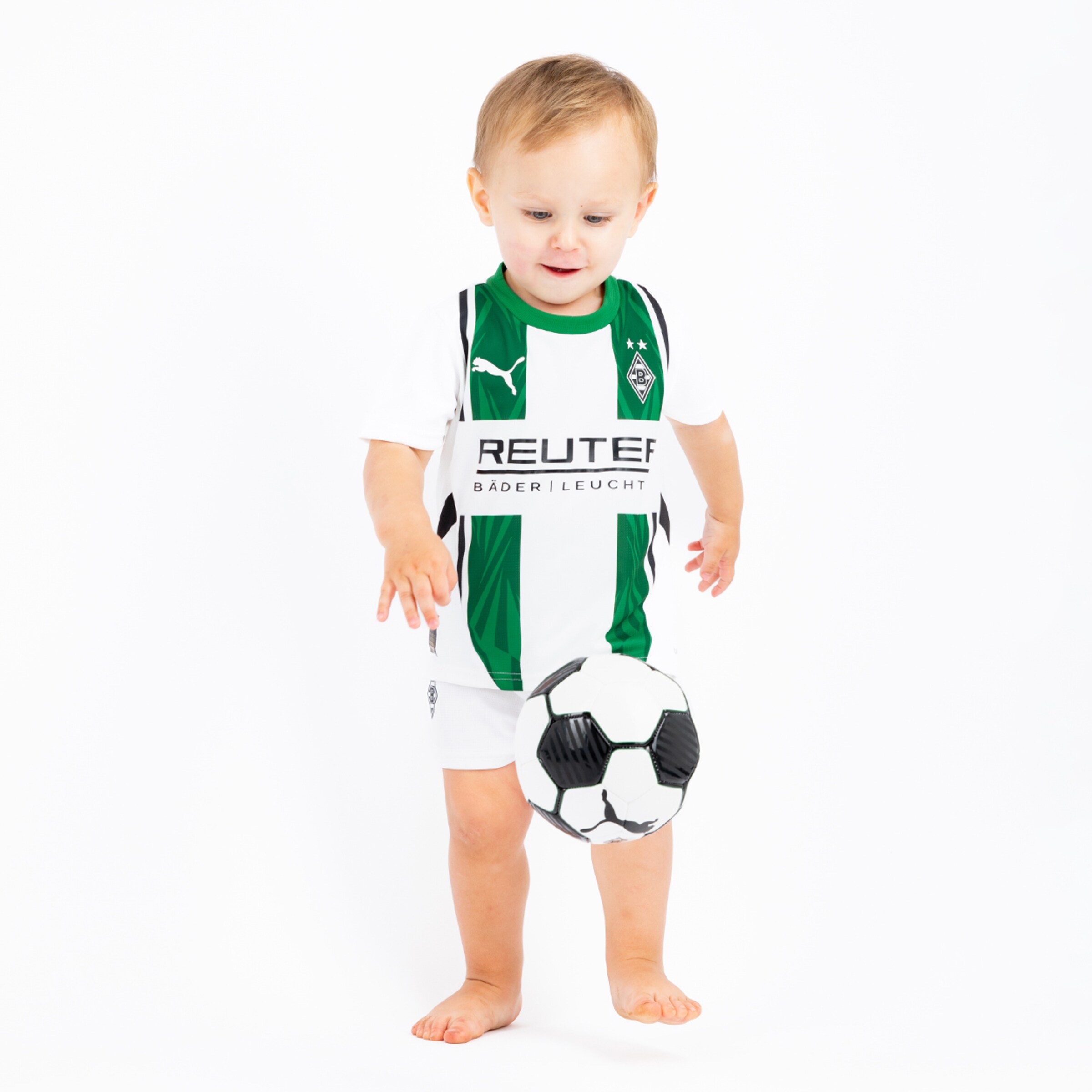 Ein Kleinkind in einem Borussia Mönchengladbach Trikot hält einen Fußball.