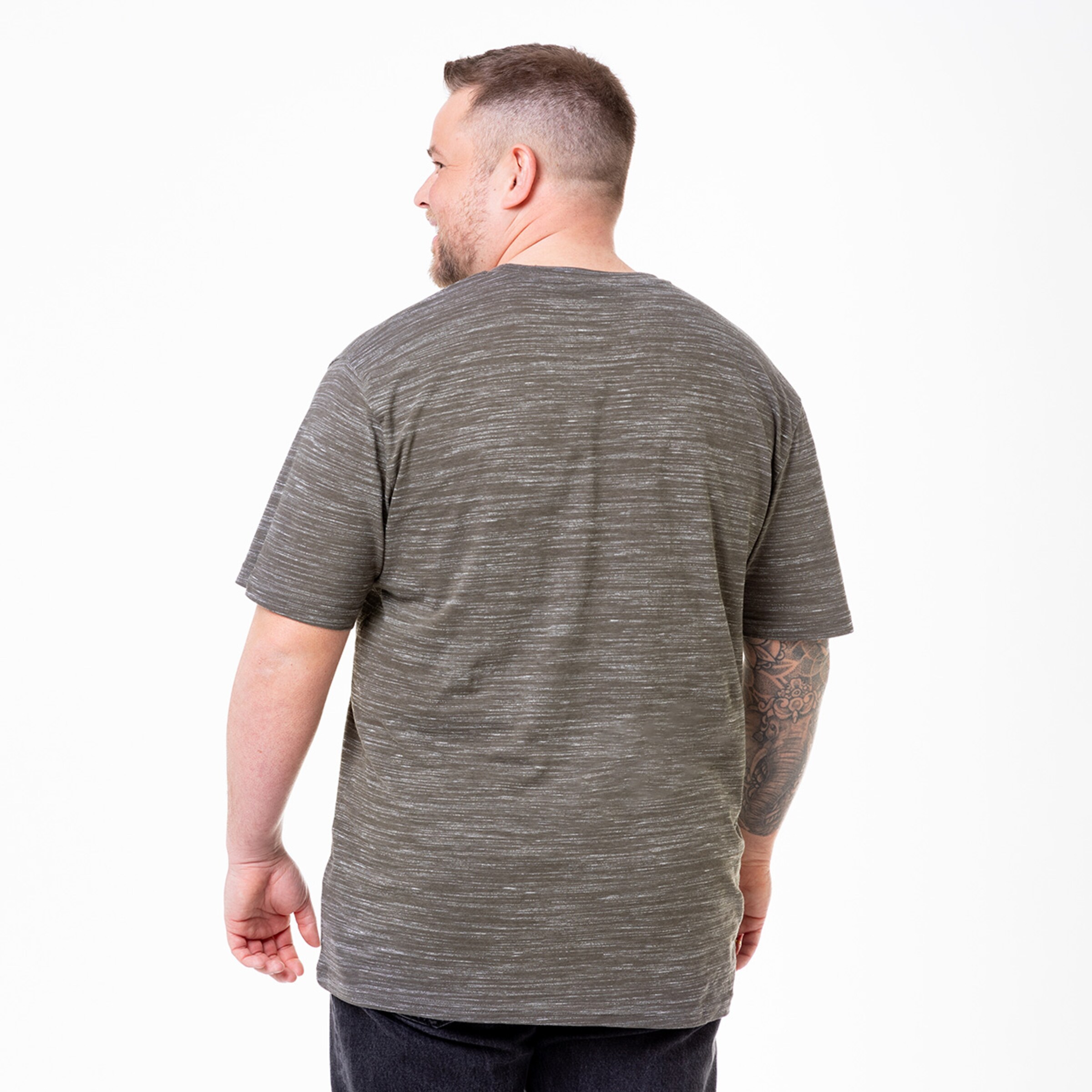 Mann im grauen T-Shirt von hinten gesehen mit Tätowierung am rechten Arm.