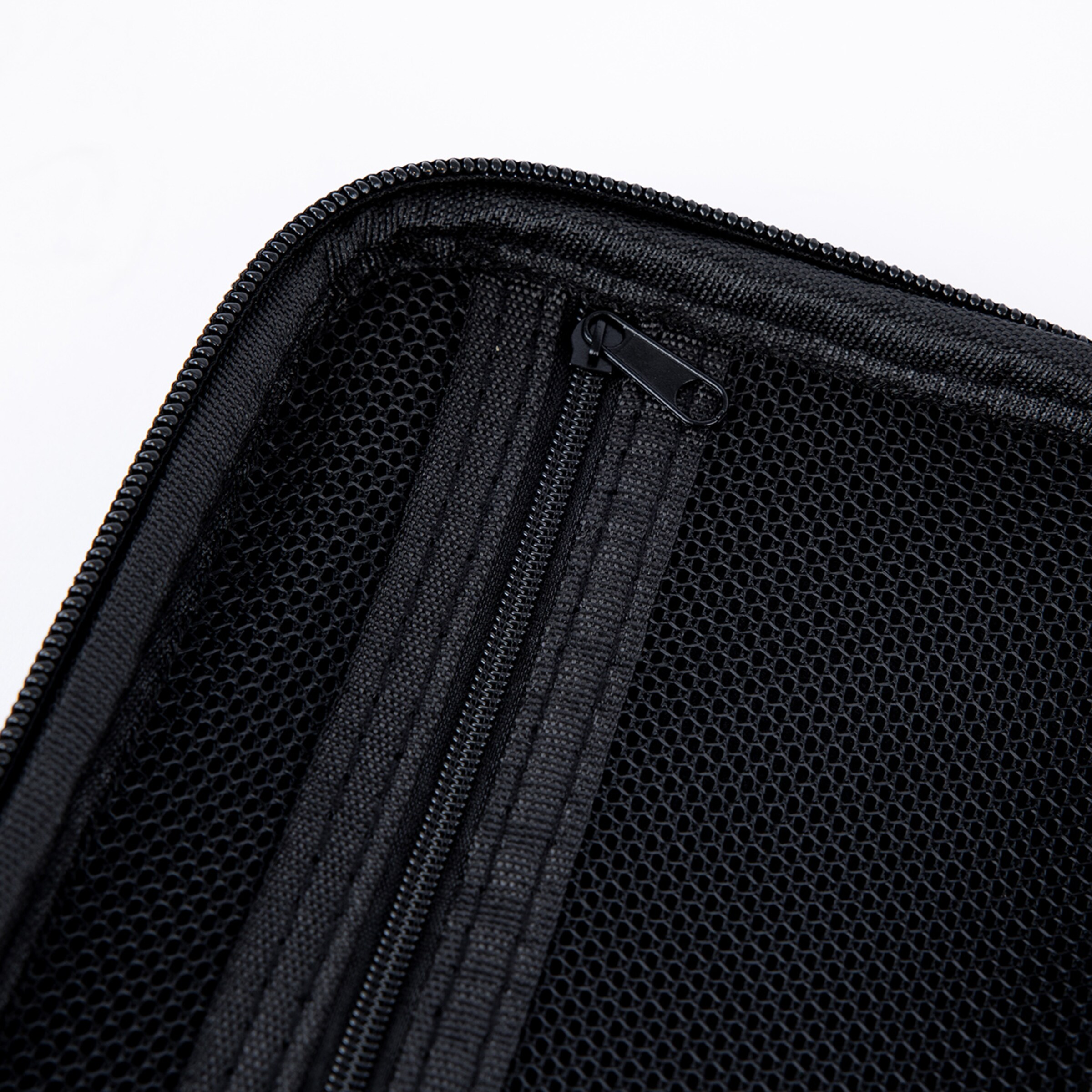 Detailaufnahme einer schwarzen Netztasche mit Reißverschluss im Inneren einer Tasche oder eines Etuis.