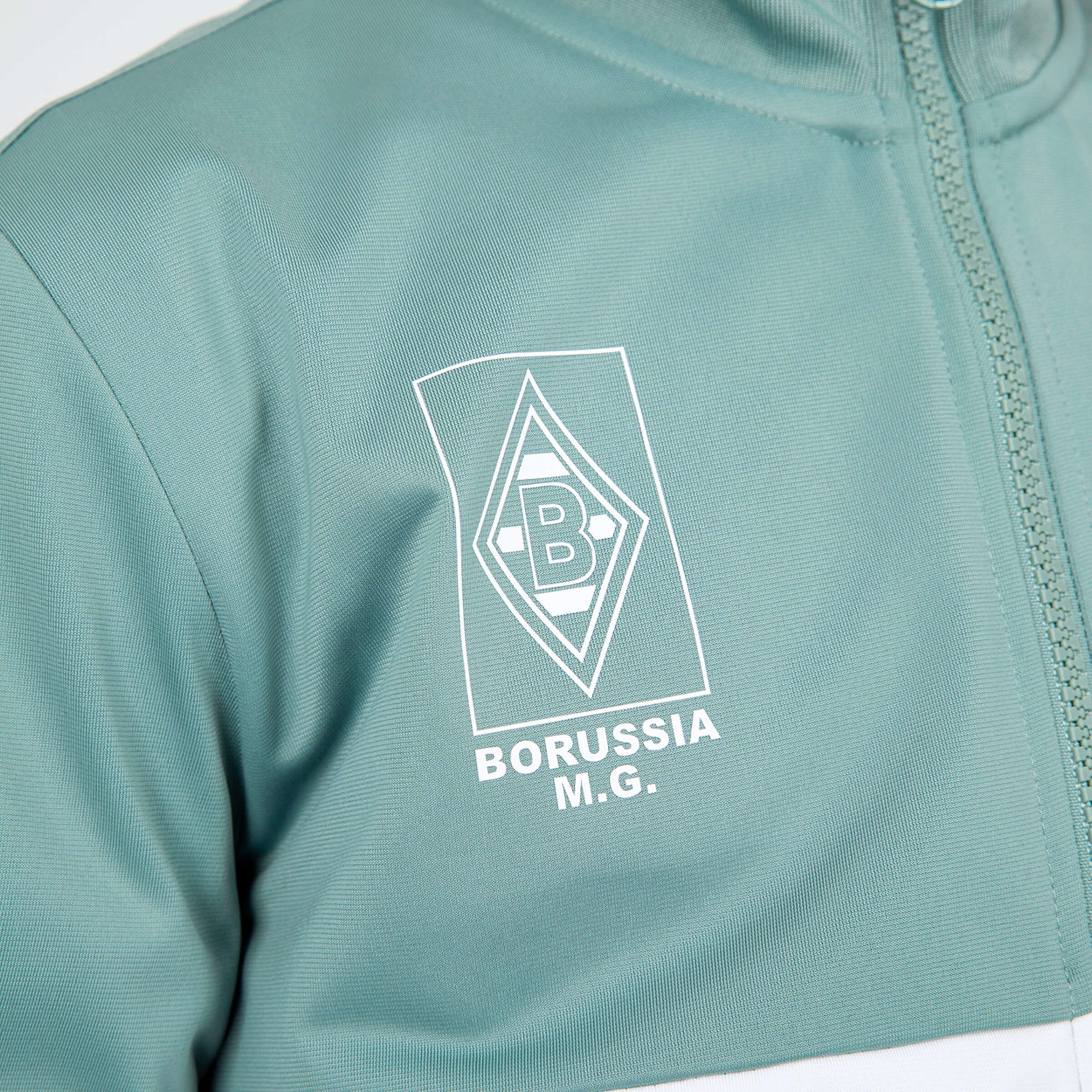 Logo von Borussia Mönchengladbach auf einer Trainingjacke in Grün.