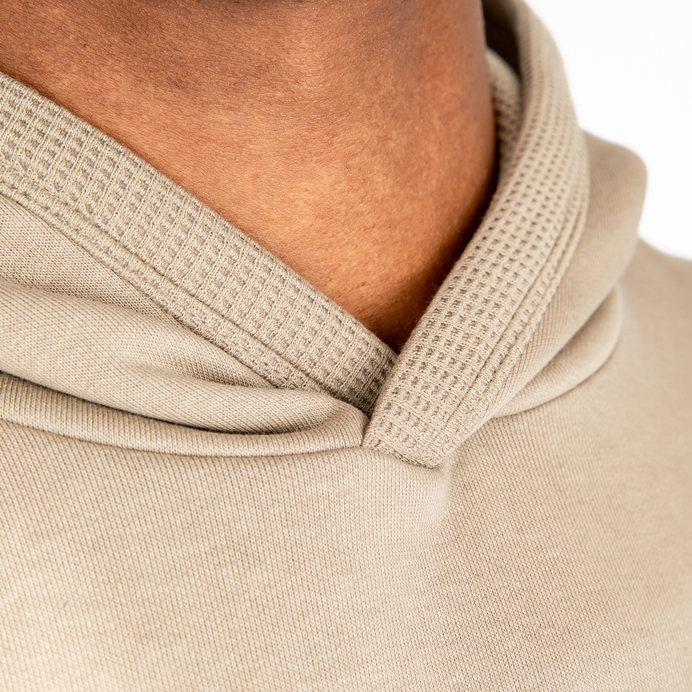 Close-up of the collar of a beige hoodie with textured lining.