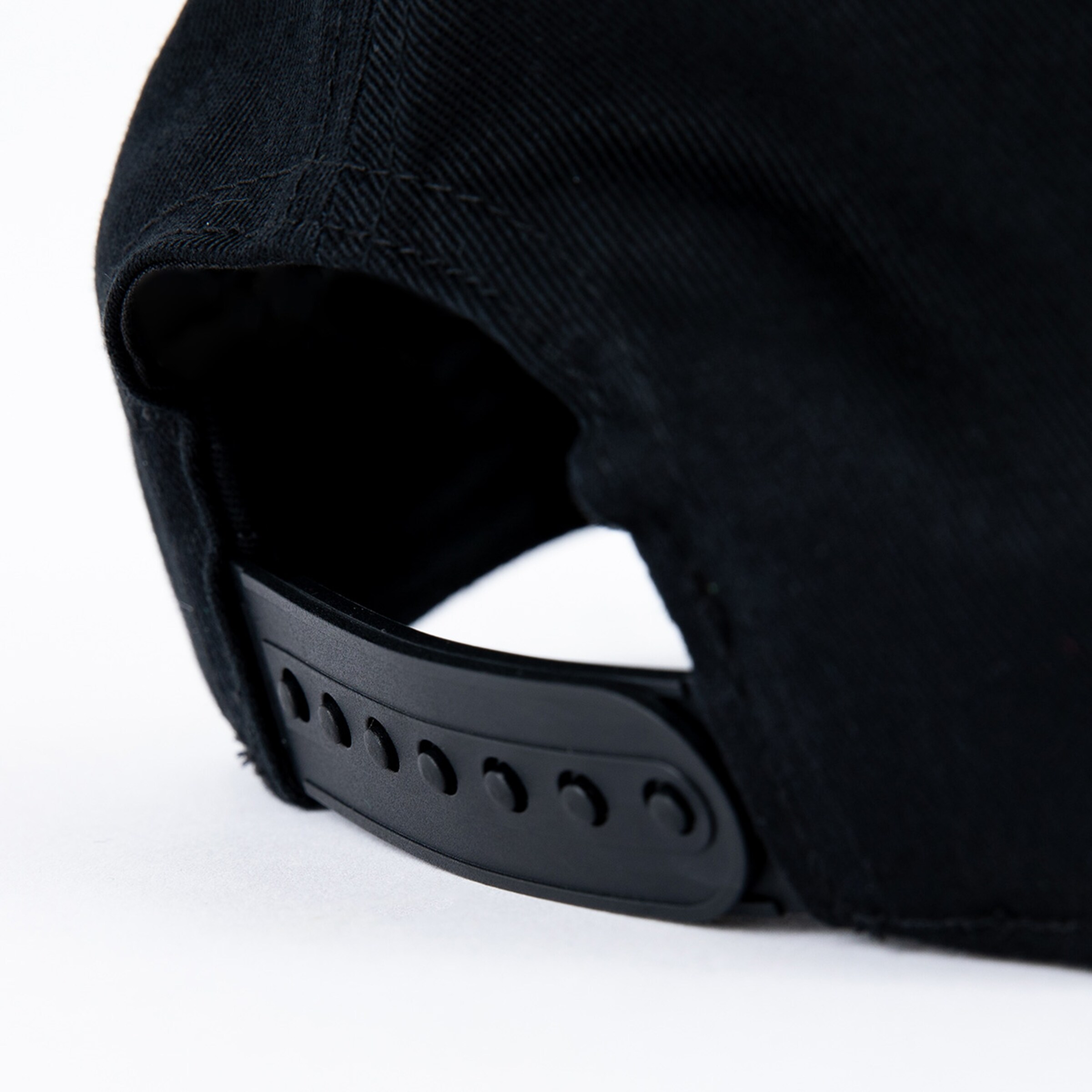 Detailansicht des Verschlusses einer schwarzen Baseballmütze.