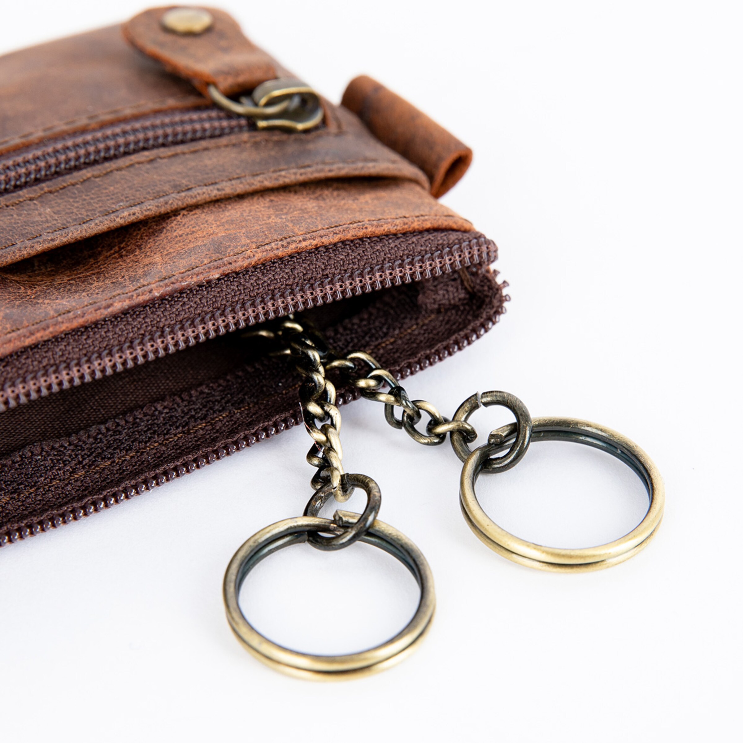 Braune Geldbörse aus Leder mit zwei Schlüsselringen und Reißverschluss.