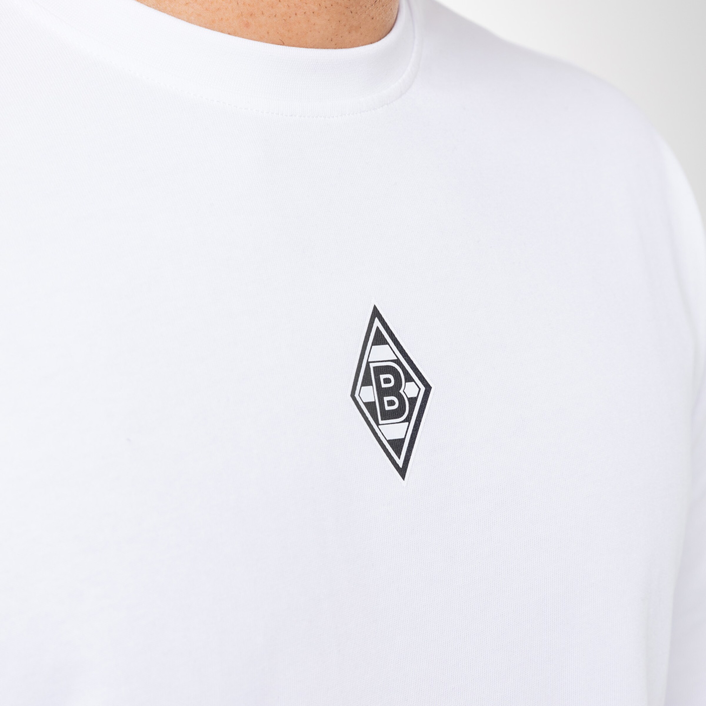 Weißes T-Shirt mit schwarzem diamantförmigem Logo von Borussia Mönchengladbach.