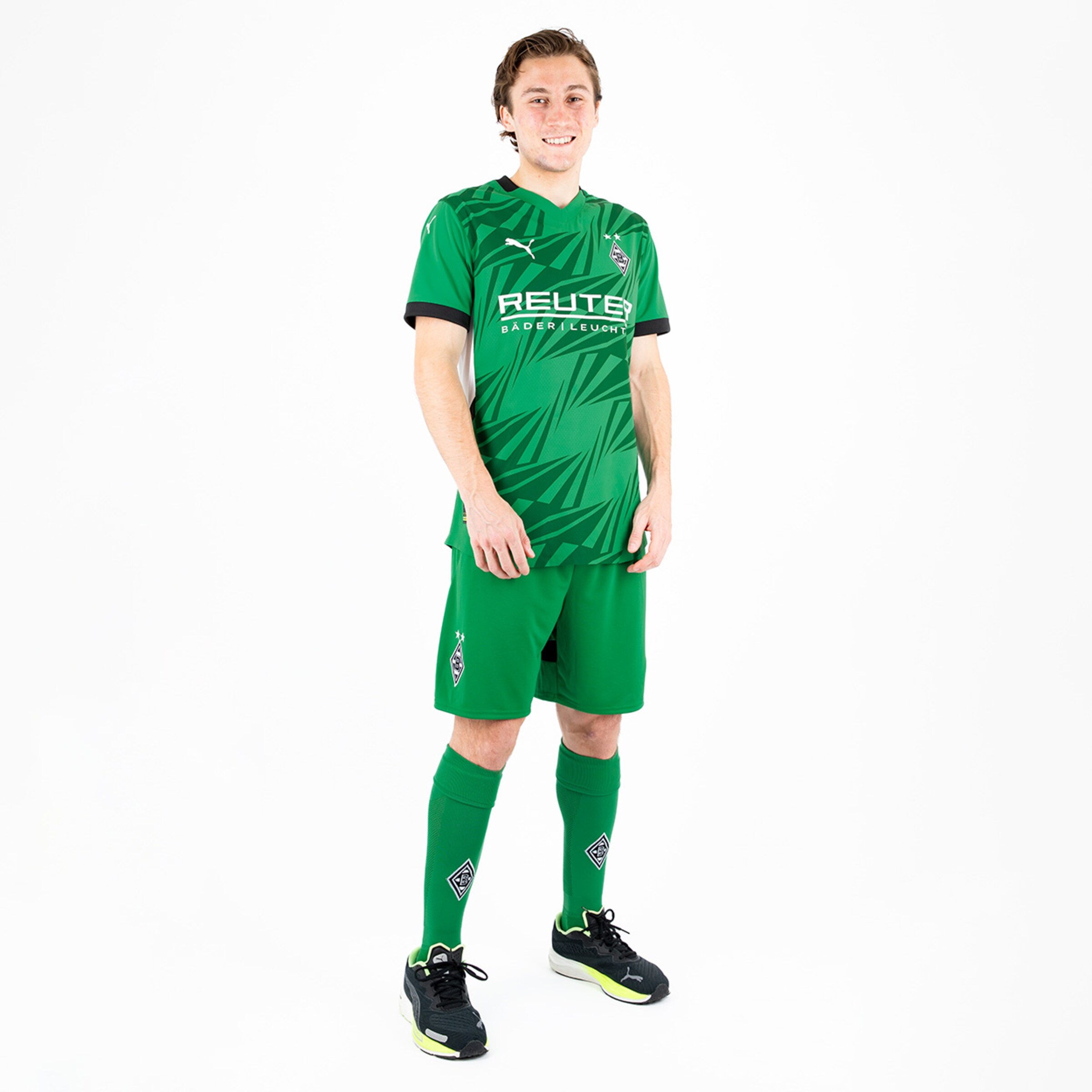 Goalkeeper in green Borussia Mönchengladbach kit standing upright with a smiling pose.