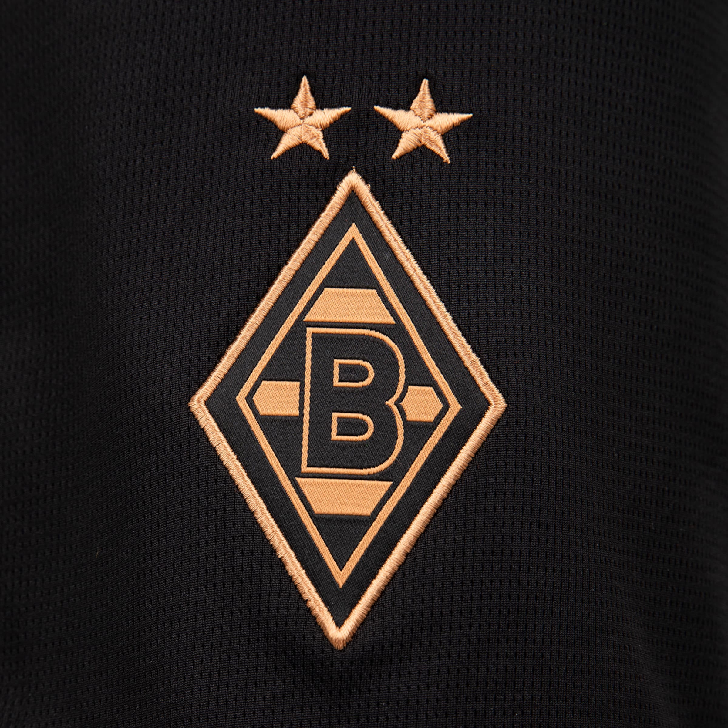 Gold-embroidered Borussia Mönchengladbach diamond logo with a 'B' and two stars on black textured fabric.