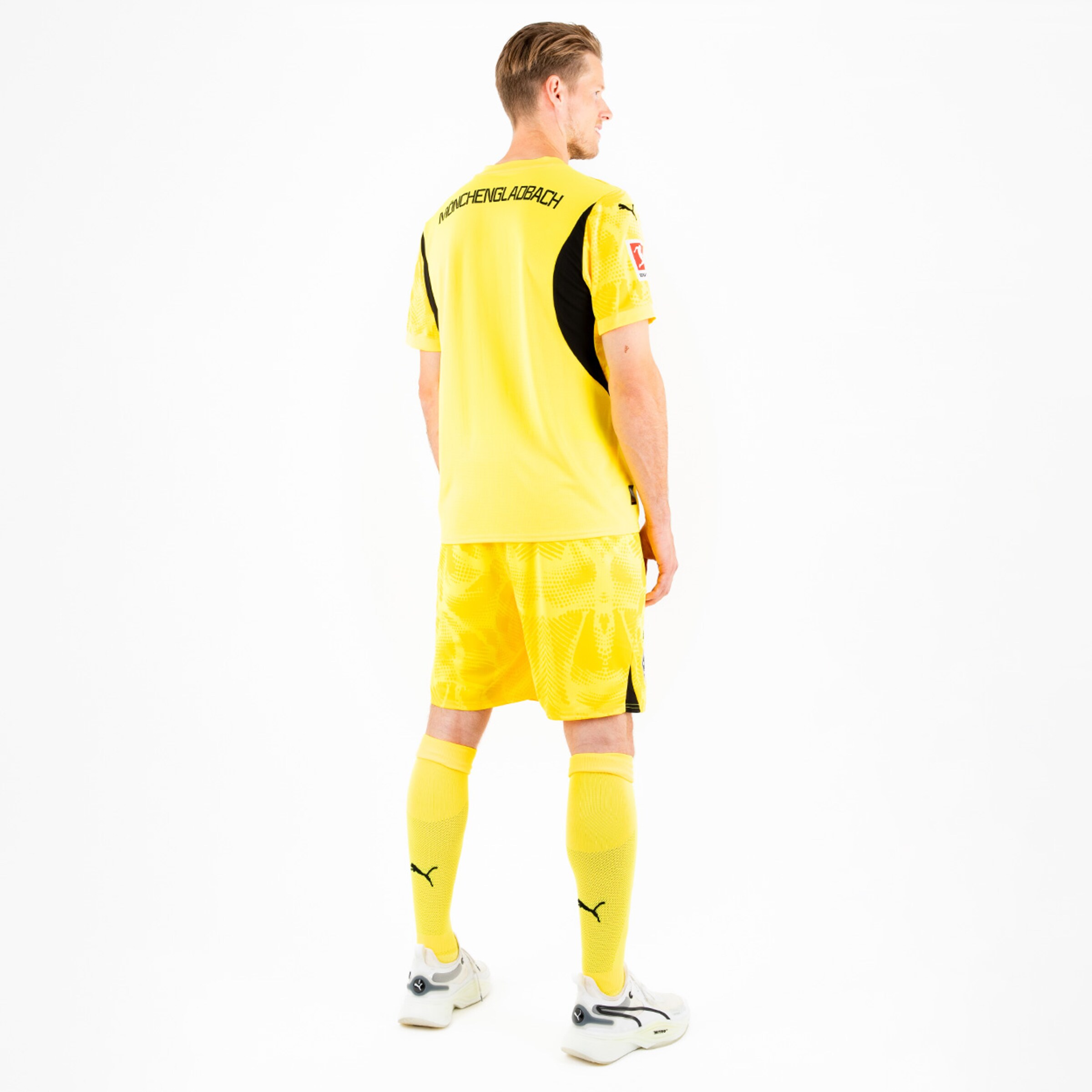 Spieler im gelben Fußballtrikot von Borussia Mönchengladbach Rückansicht.
