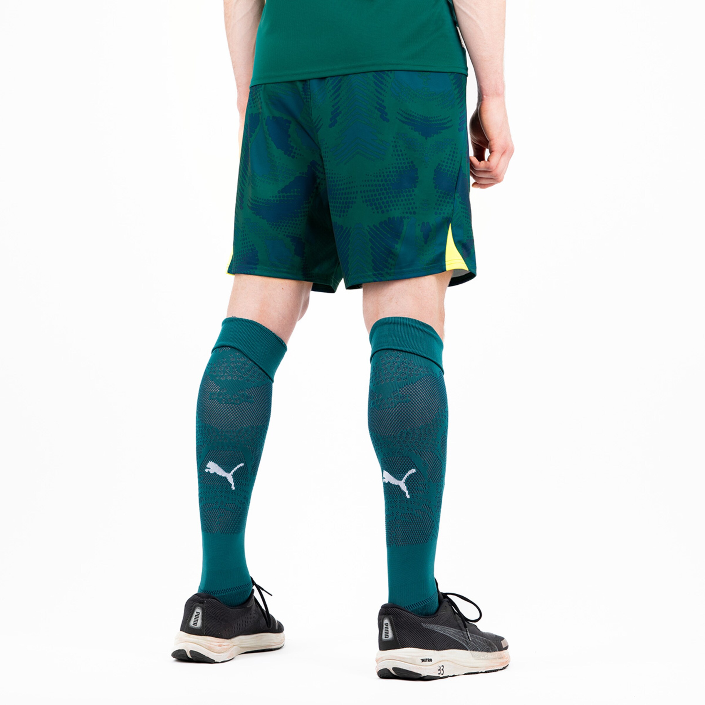 Mann von hinten in Sportausrüstung trägt grüne Shorts und Socken mit Puma-Logo.