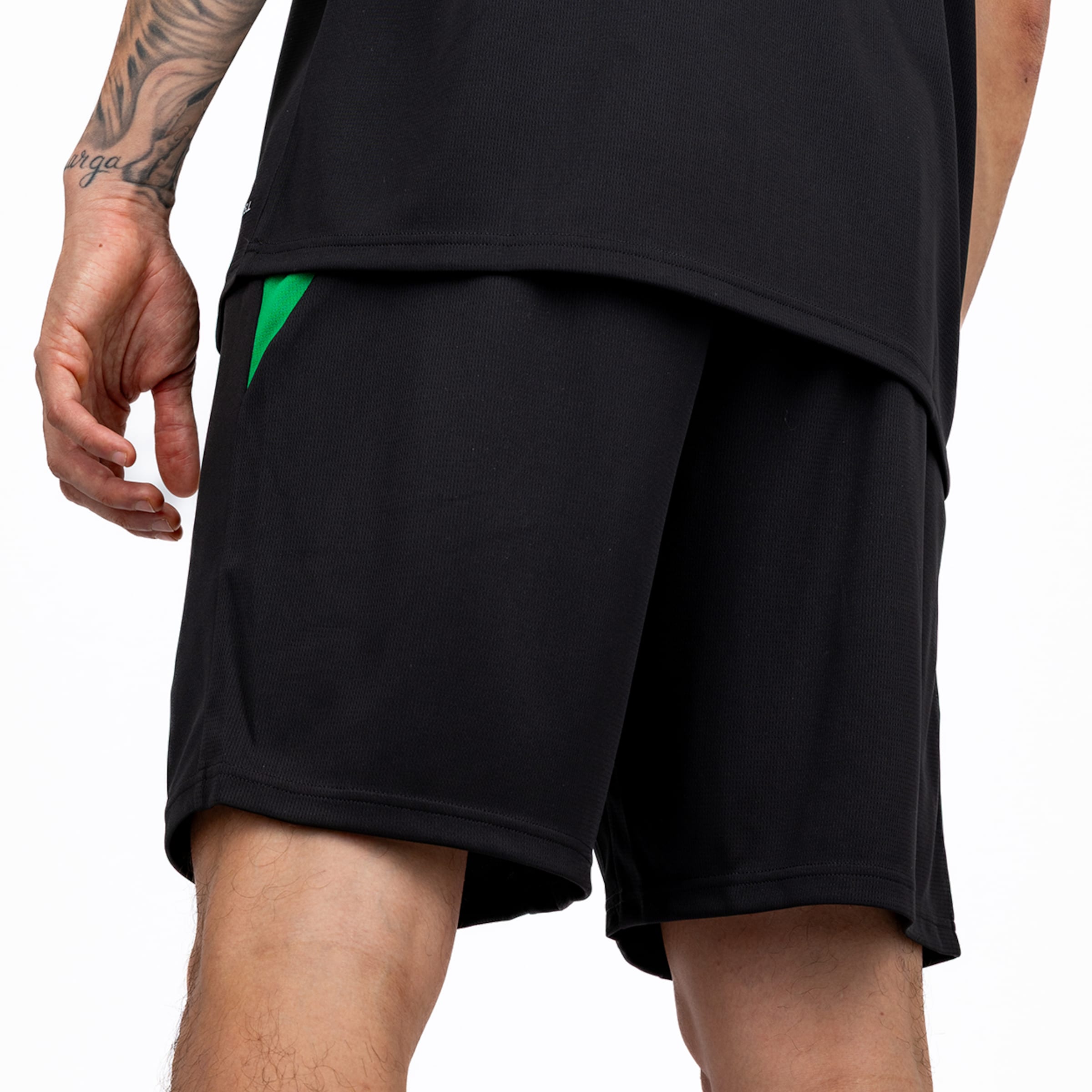 Nahaufnahme von hinten: Schwarze Sportshorts mit grünem Akzent und passendes schwarzes T-Shirt vor weißem Hintergrund.