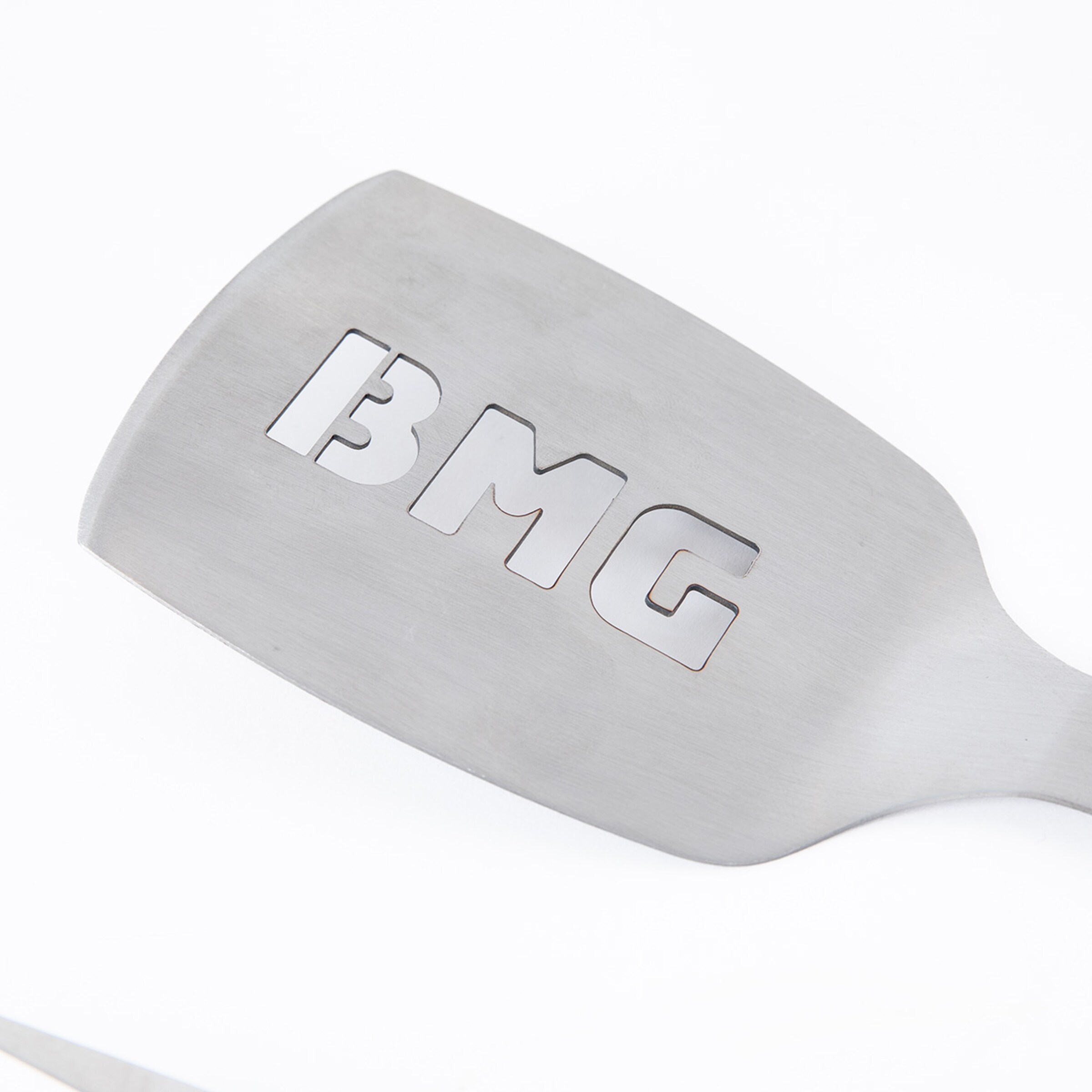 Stainless steel spatula with cut-out BMG logo.
