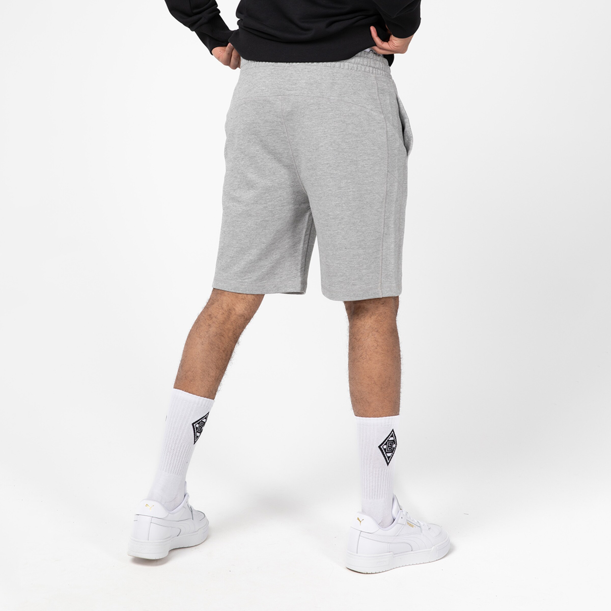 Mann steht mit dem Rücken zur Kamera in grauen Shorts und weißen Socken.