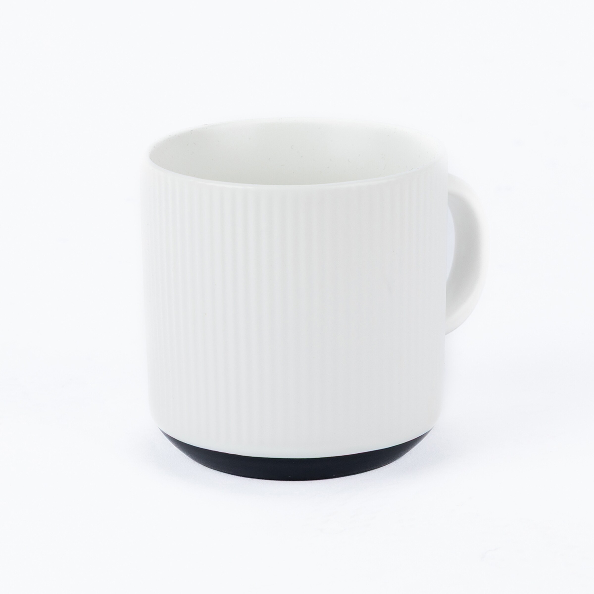 Weiße Keramiktasse mit vertikaler Riffelung und schwarzem Boden auf weißem Hintergrund.