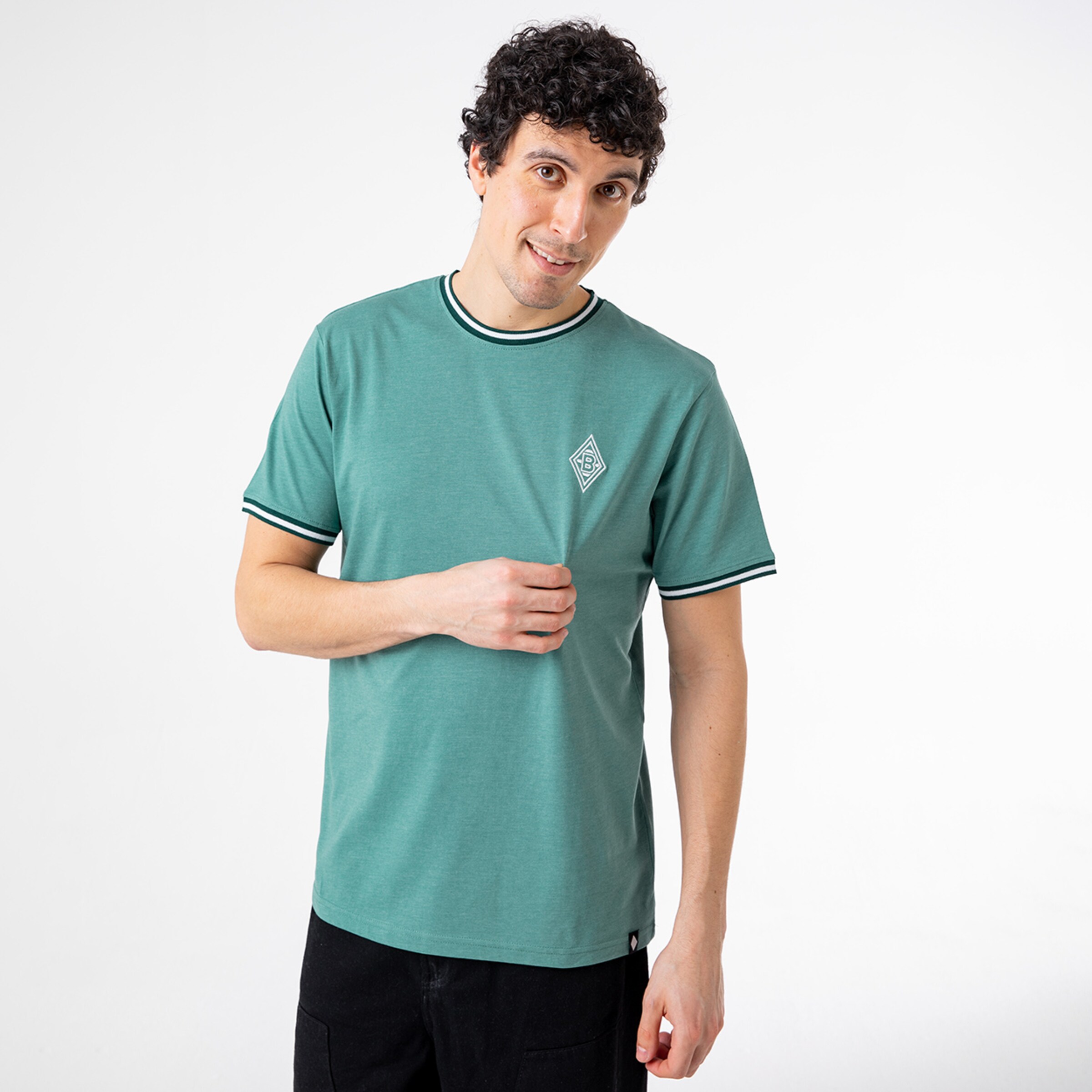 Man with curly hair wearing a green T-shirt featuring an emblem.