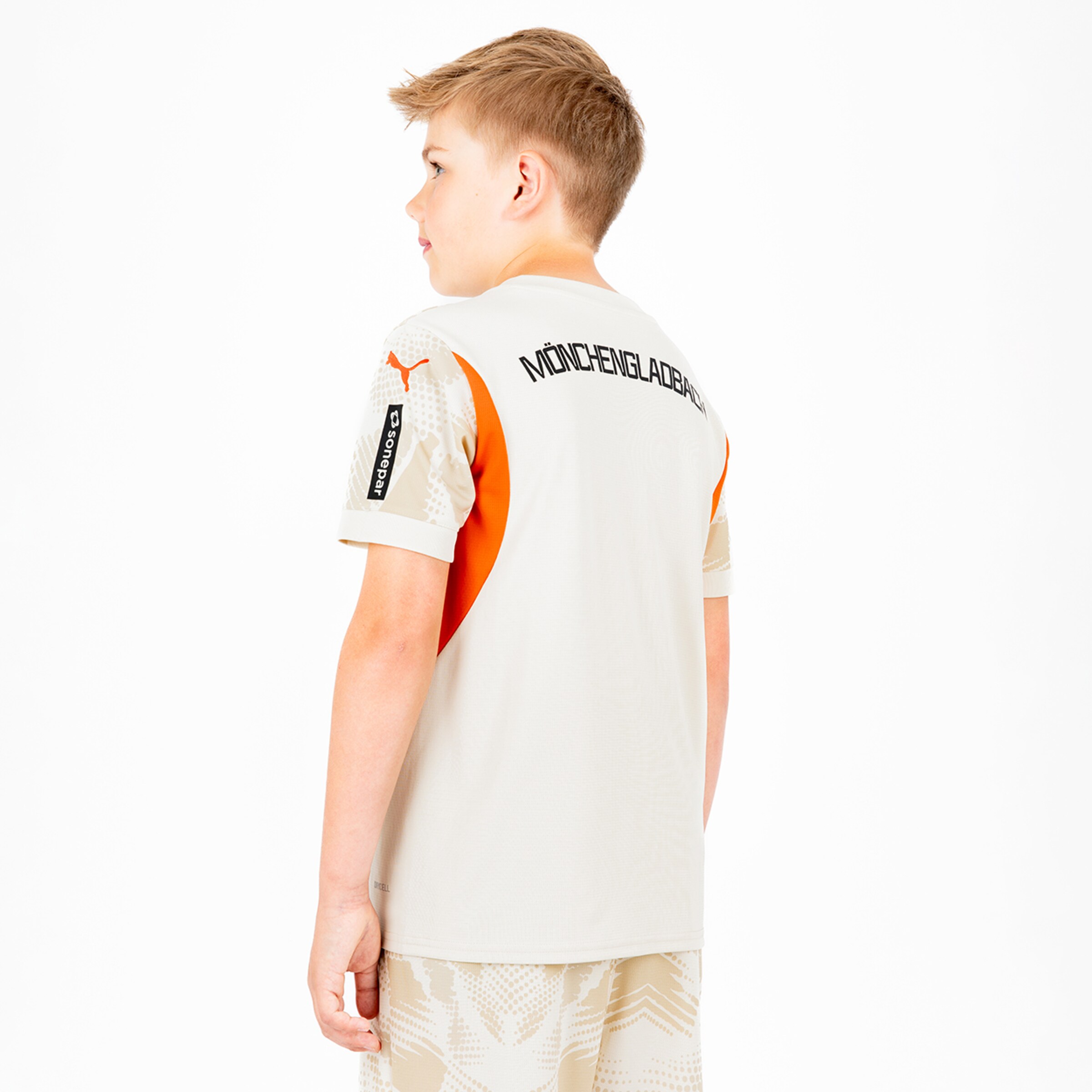 Ein Junge trägt ein leichtes Trikot mit dem Aufdruck MÖNCHENGLADBACH auf dem Rücken.