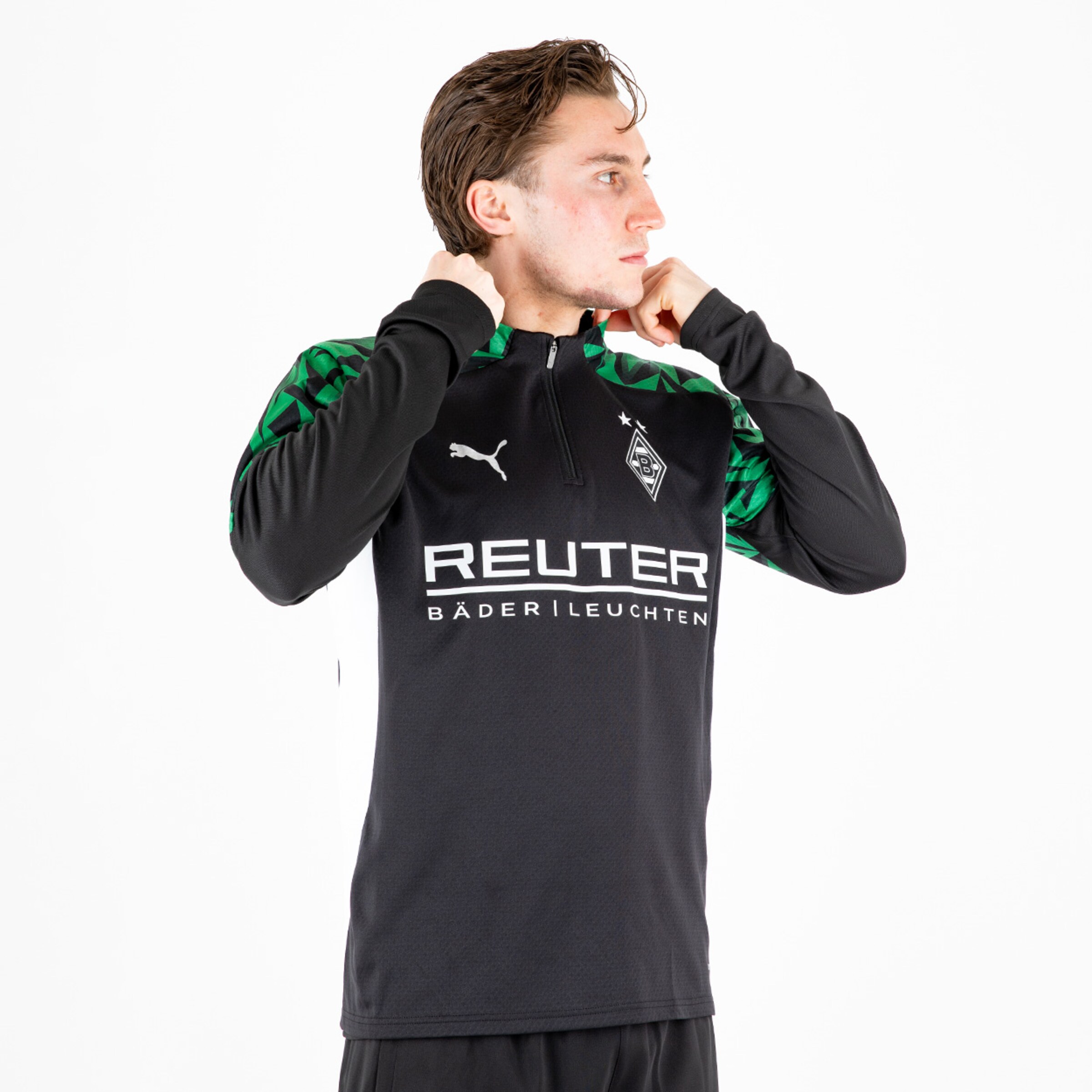 Player wearing a black training top with a zip and green design featuring Borussia Mönchengladbach and Puma logos.