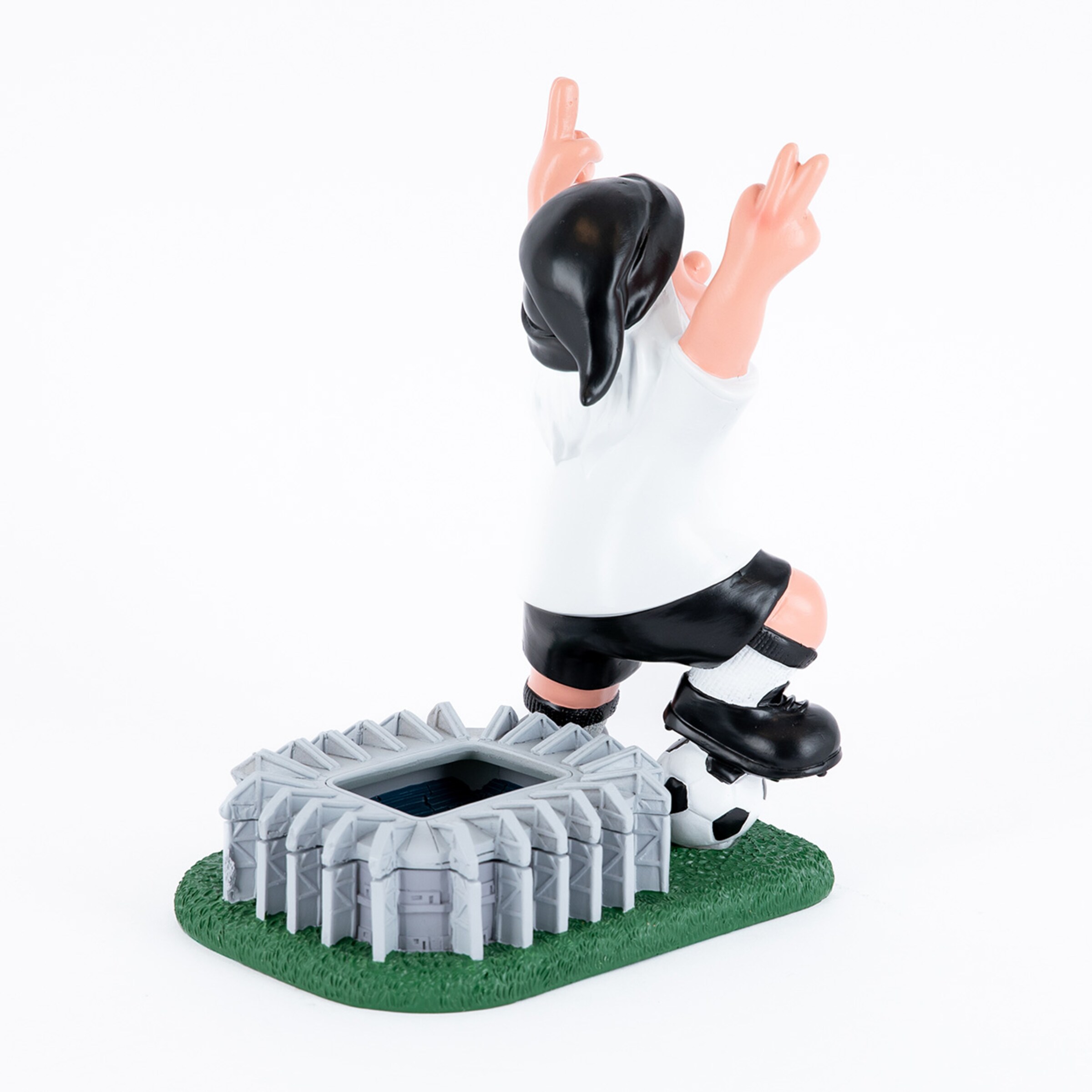 Eine Figur eines Fußballspielers mit freudiger Pose und zwei erhobenen Fingern vor einem Stadionmodell.