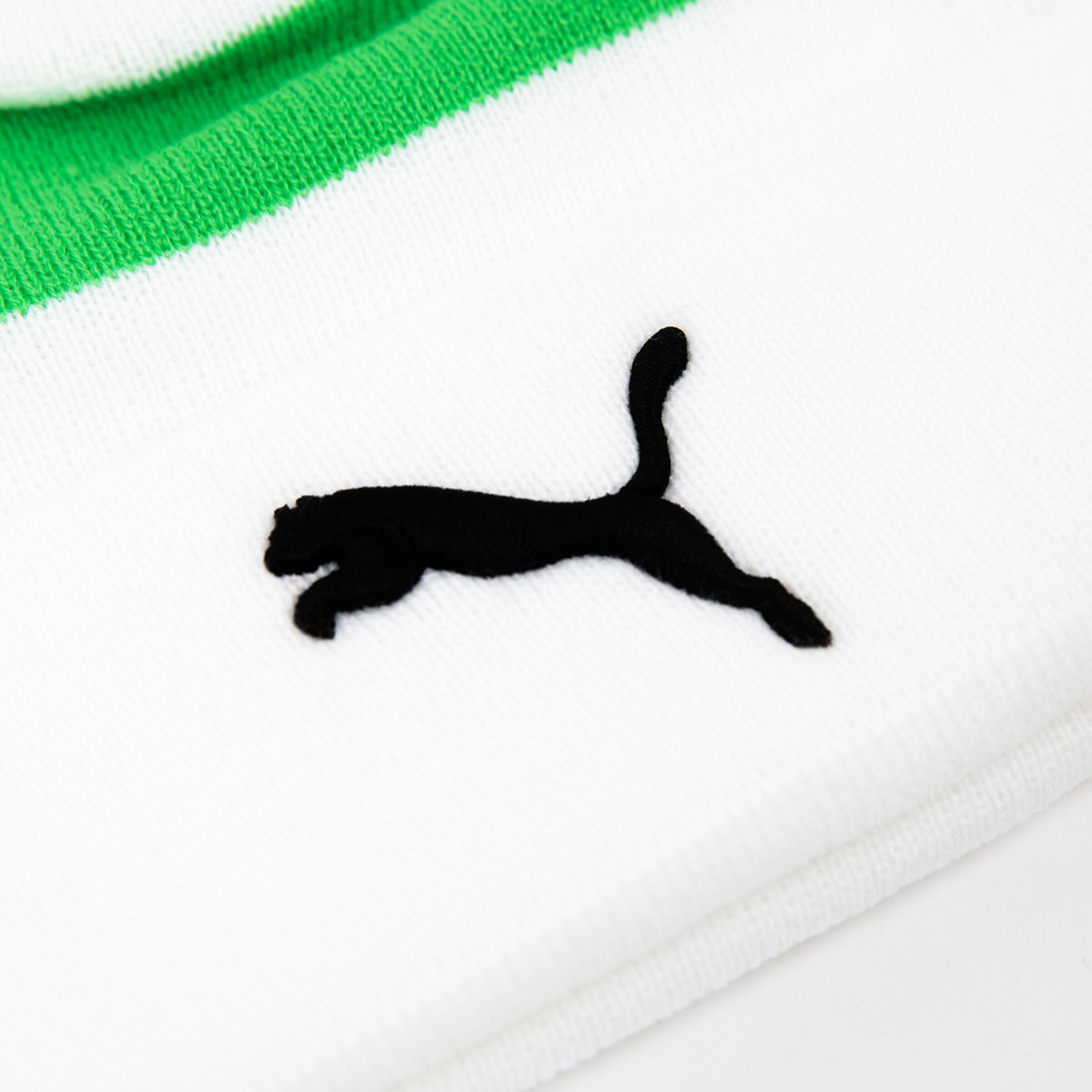 Schwarz-weißer Puma-Logo auf einem weißen Socken mit grünen Streifen