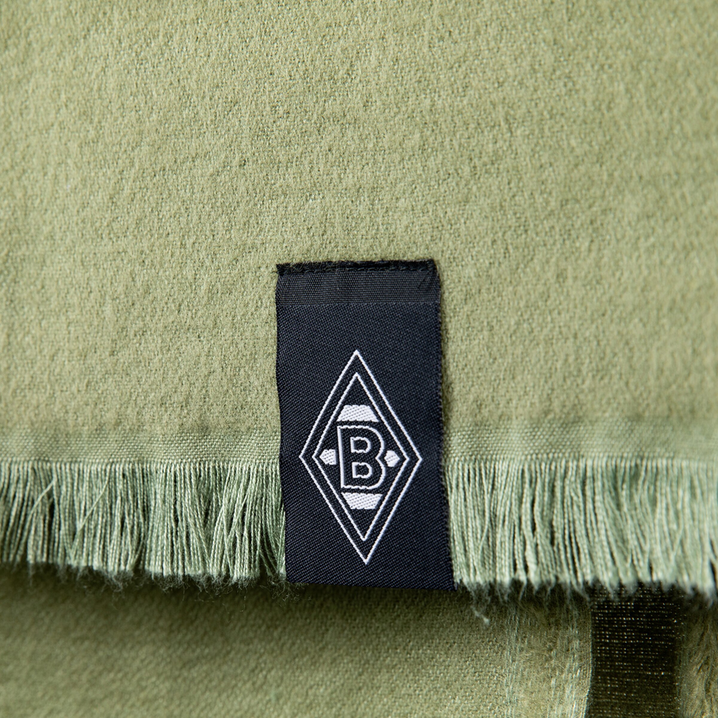 Nahaufnahme eines grünen Schals mit einem schwarzen Etikett und dem Logo von Borussia Mönchengladbach.