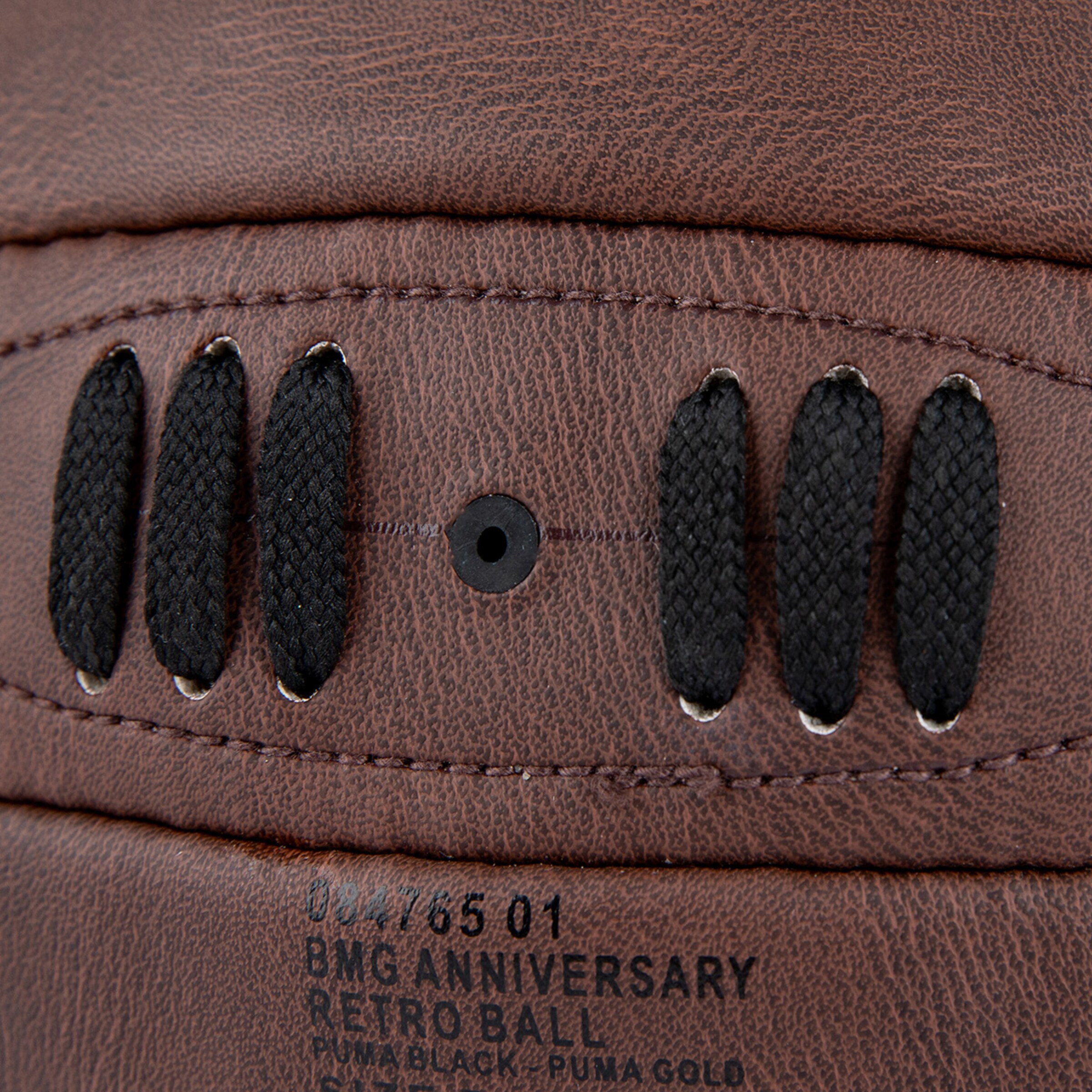 Nahaufnahme eines braunen Puma BMG Anniversary Retro-Fußballs mit schwarzer Schnürung, Ventil und aufgedrucktem Text.