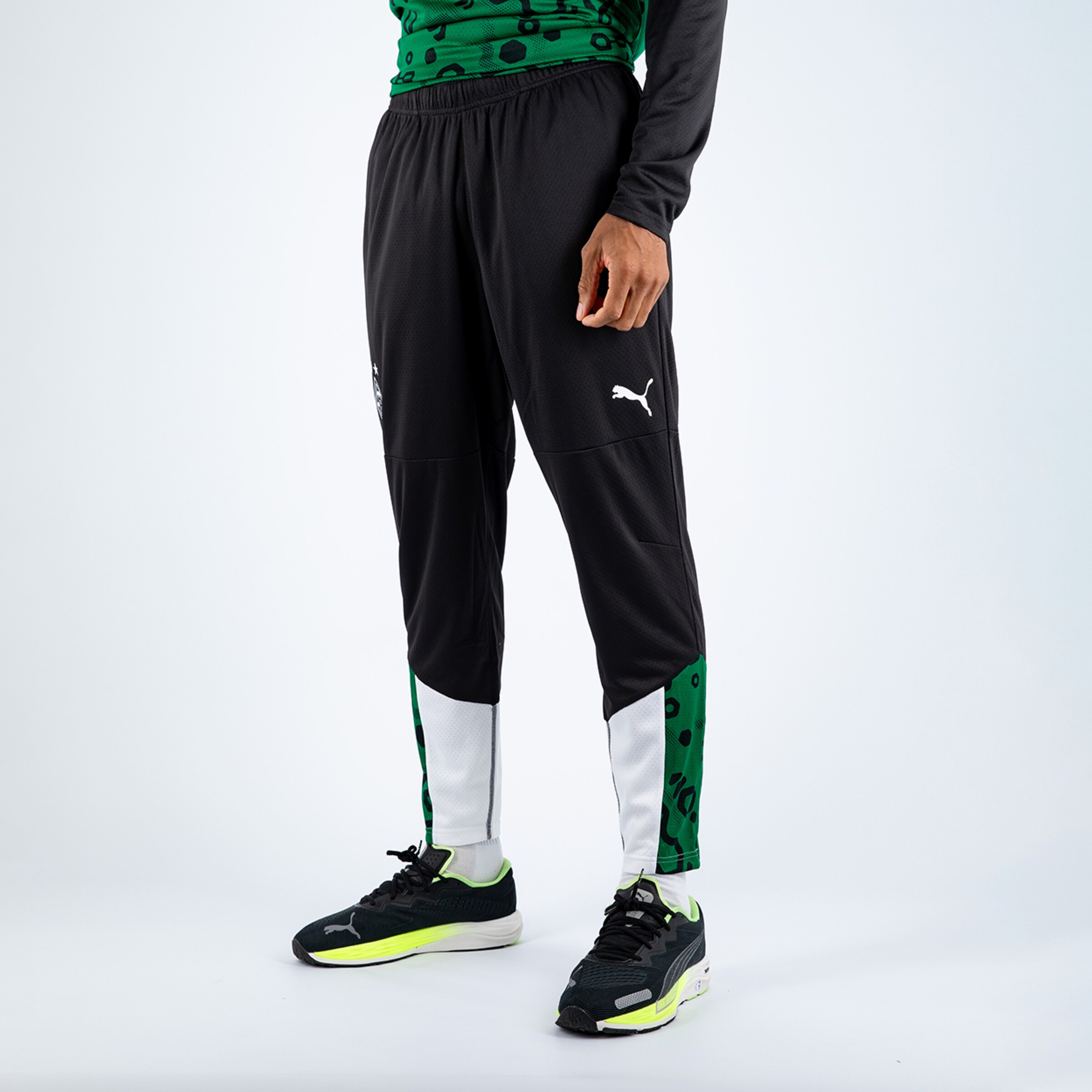 Schwarze Trainingshose mit grünem und weißem Seitendesign und Puma-Logo.