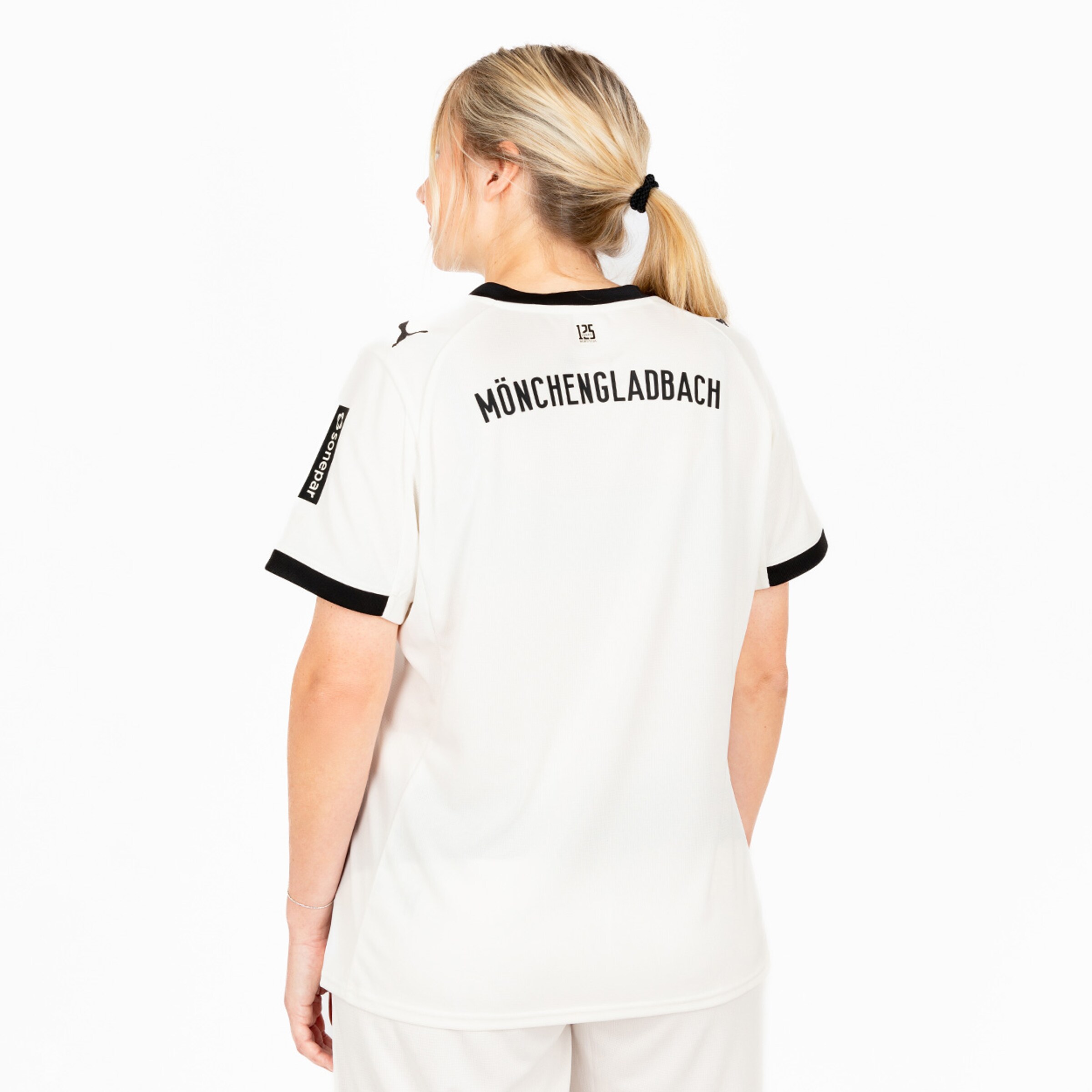 Rückansicht eines weißen Borussia Mönchengladbach Trikots mit schwarzem Kragen und Schriftzug MÖNCHENGLADBACH.