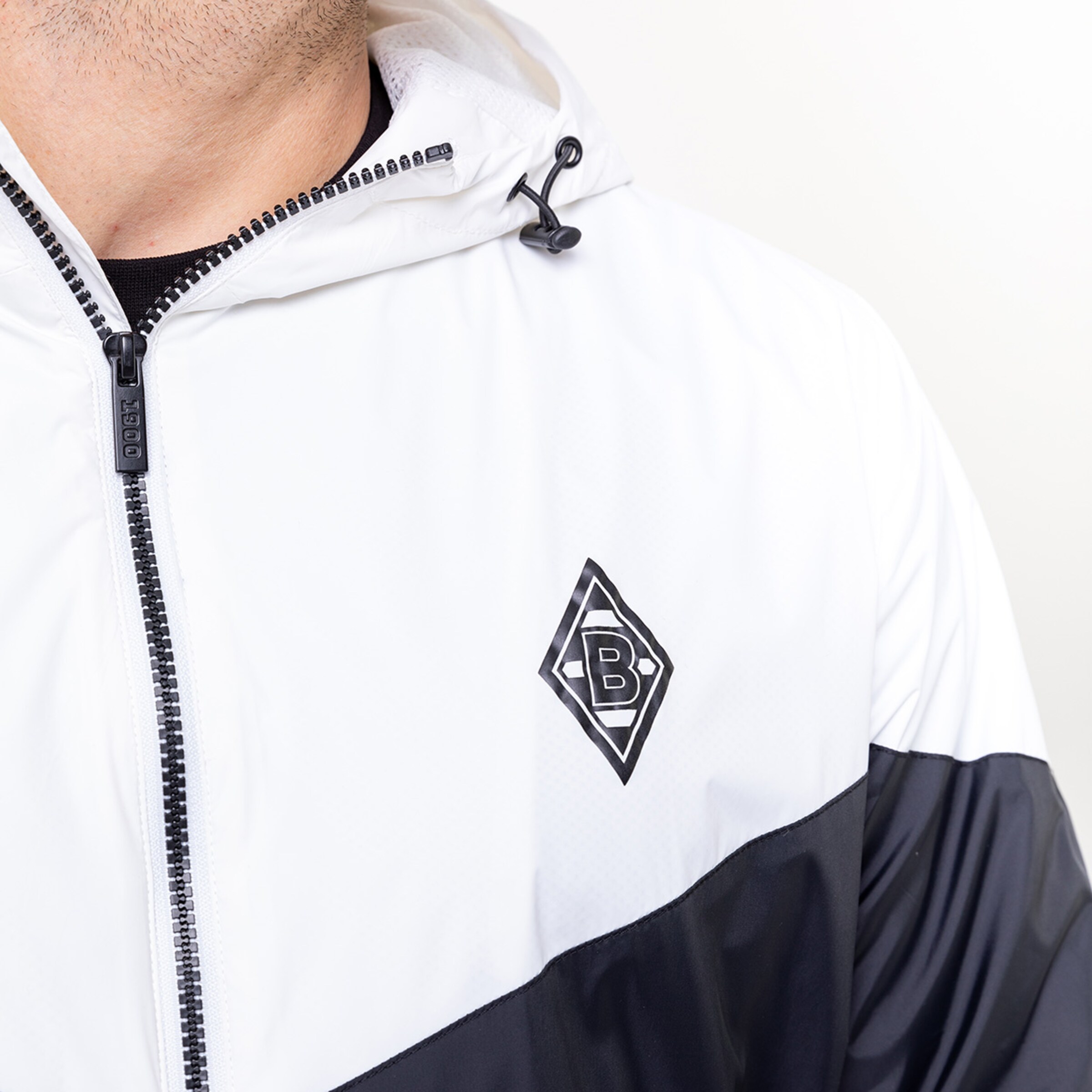 Close-up of a person wearing a white and black jacket featuring Borussia Mönchengladbach logo.