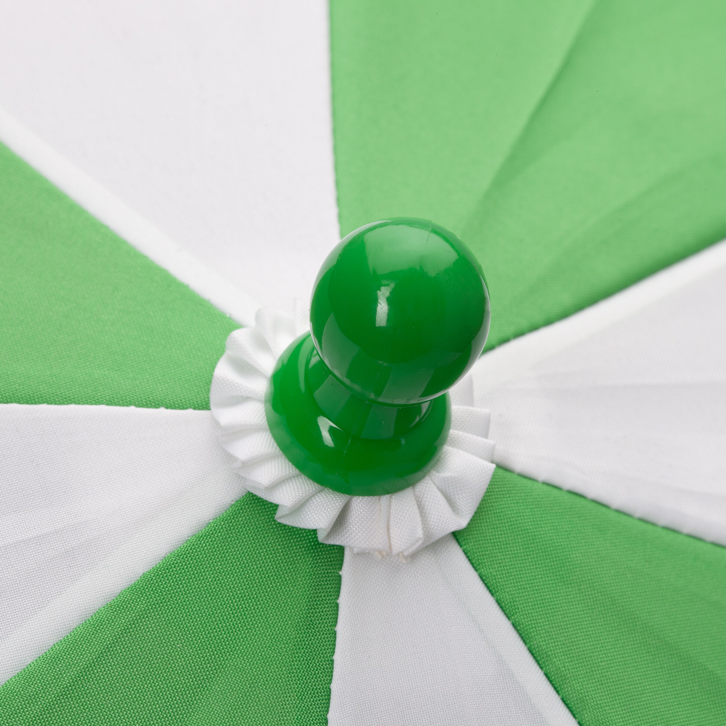 Grüner Schirmknopf aus Kunststoff auf einem weißen und grünen Sonnenschirm.