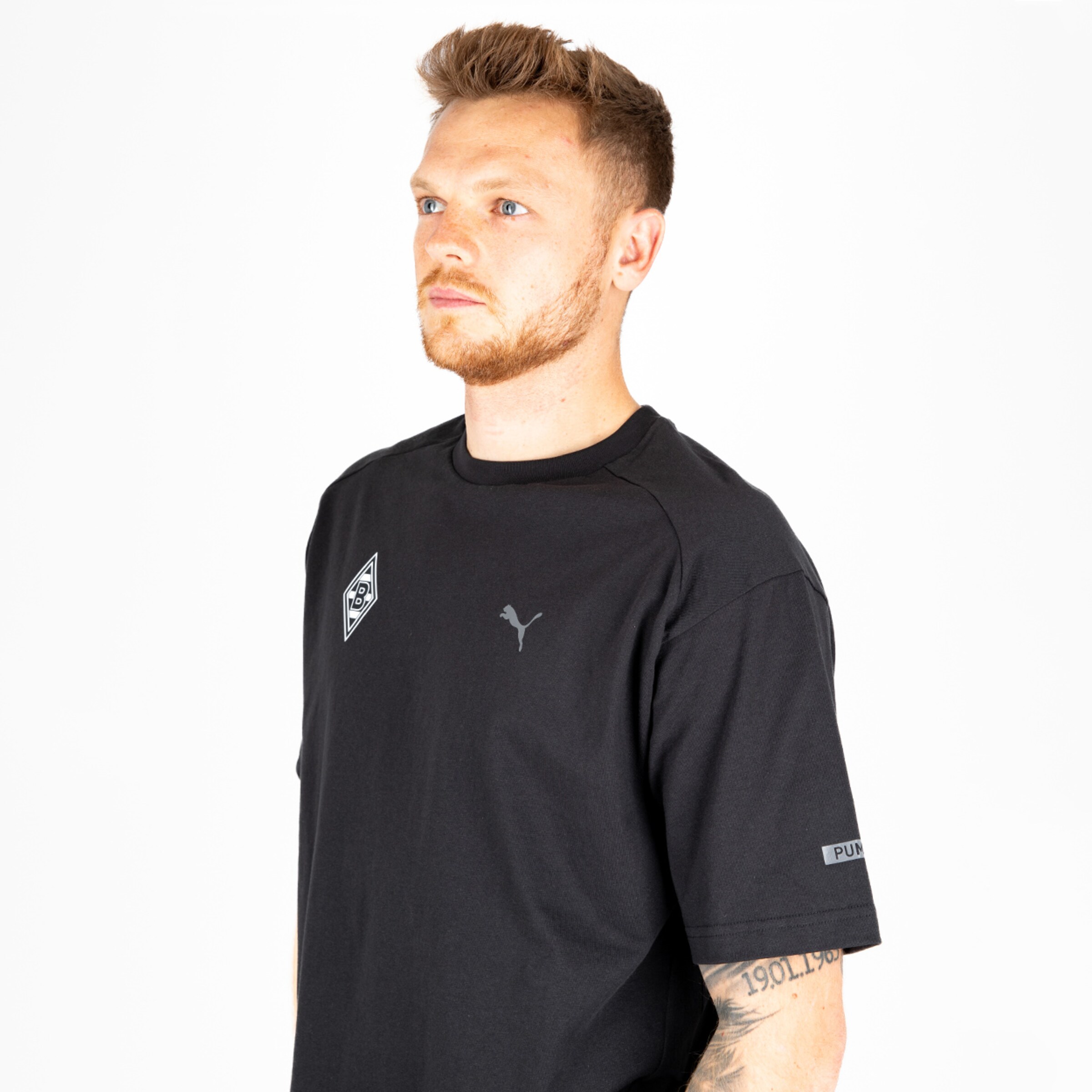 Man wearing a black shirt with PUMA logo and Borussia Mönchengladbach emblem.