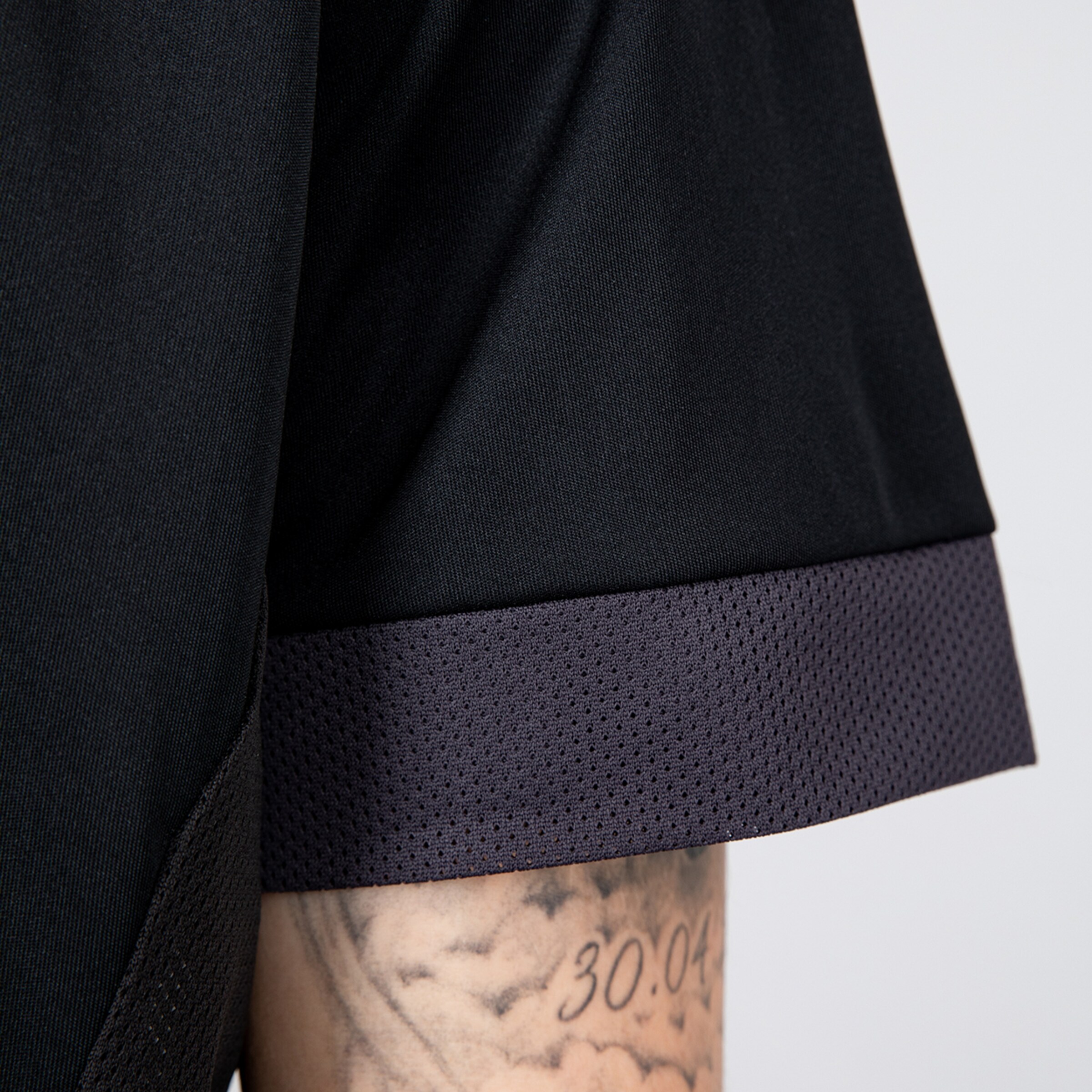 Close-up of a black jersey featuring a purple mesh-like hem.