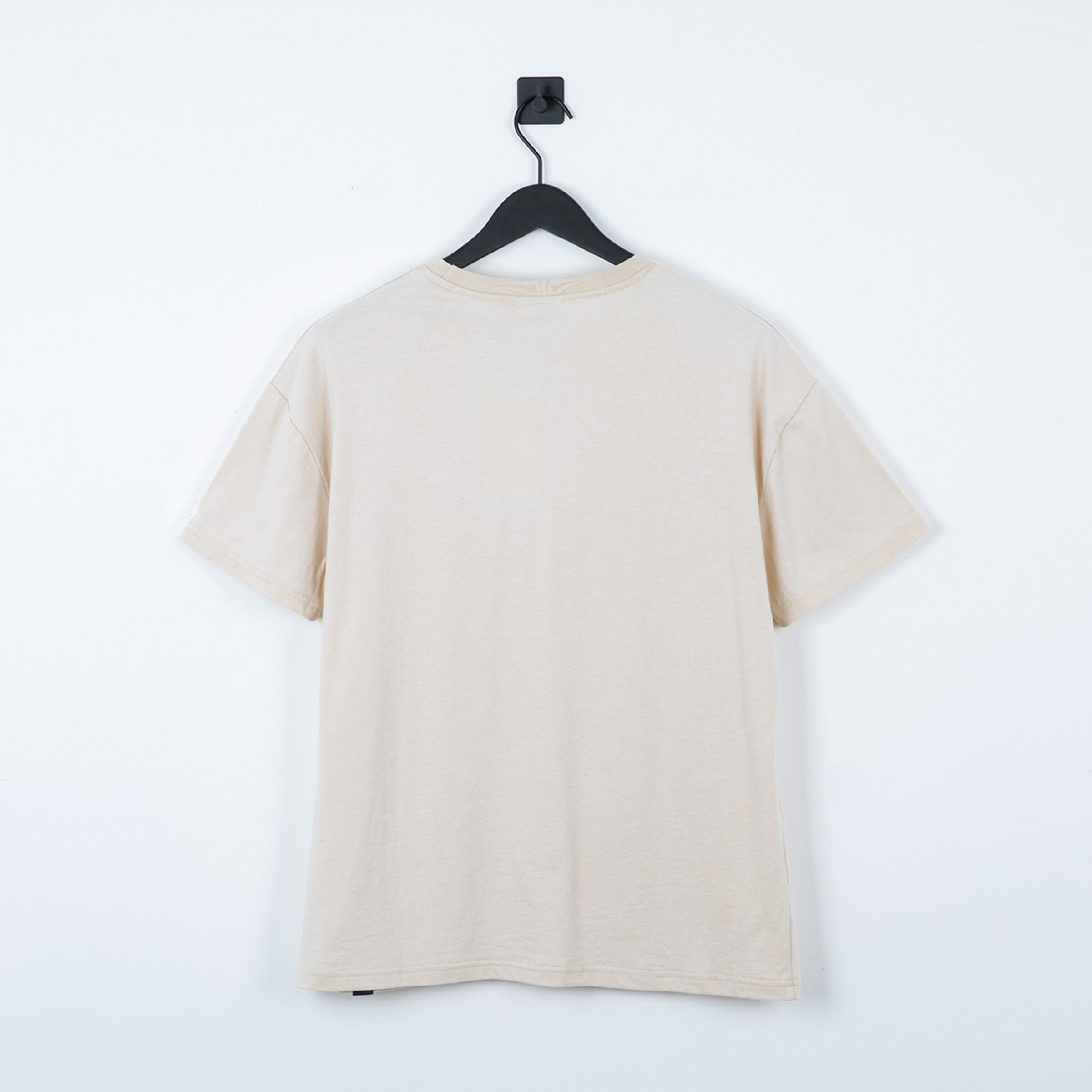 Hellbeige T-Shirt mit kurzen Ärmeln von hinten betrachtet an einem Kleiderbügel hängend.