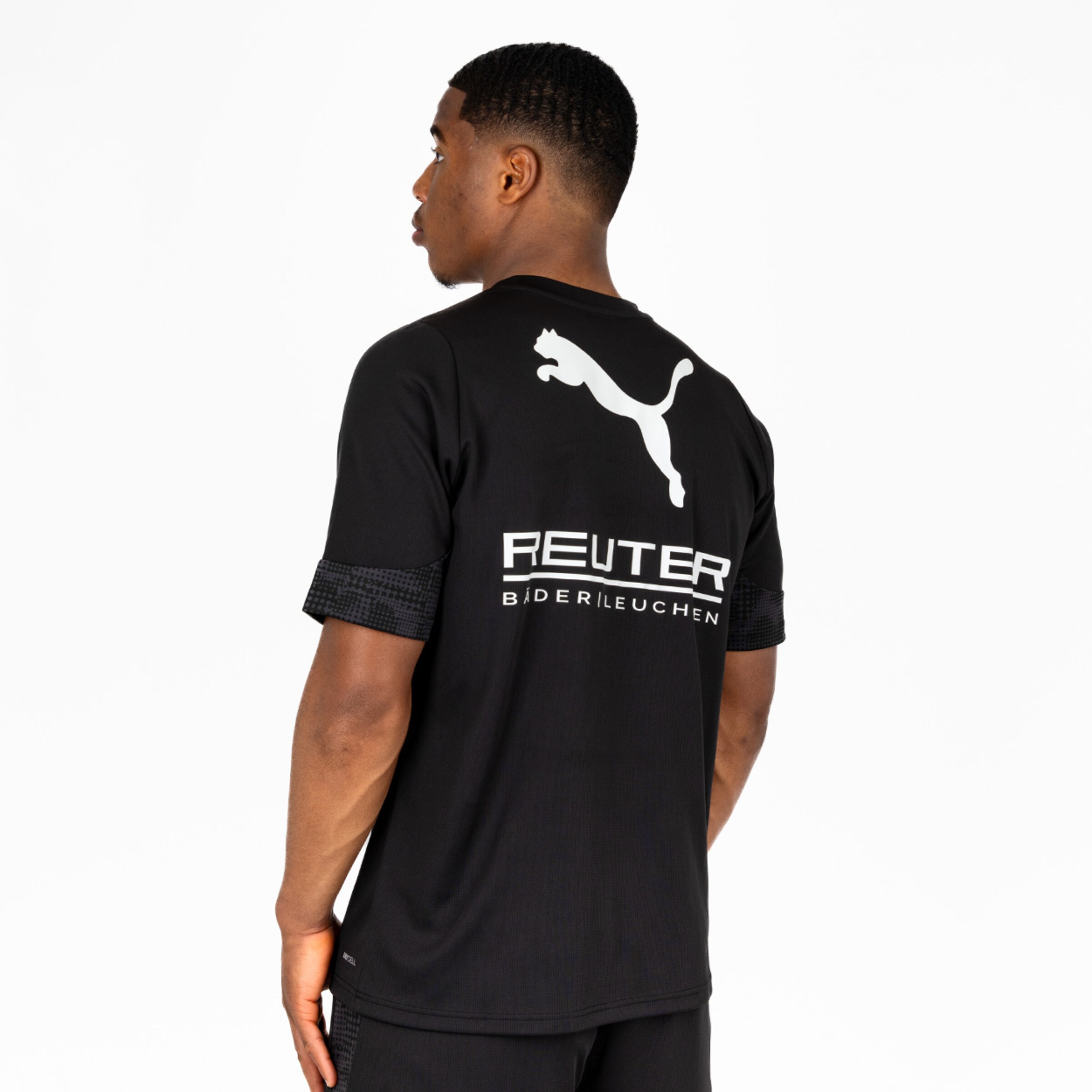 Mann trägt ein schwarzes T-Shirt mit Puma-Logo und Sponsorenaufdruck auf dem Rücken.