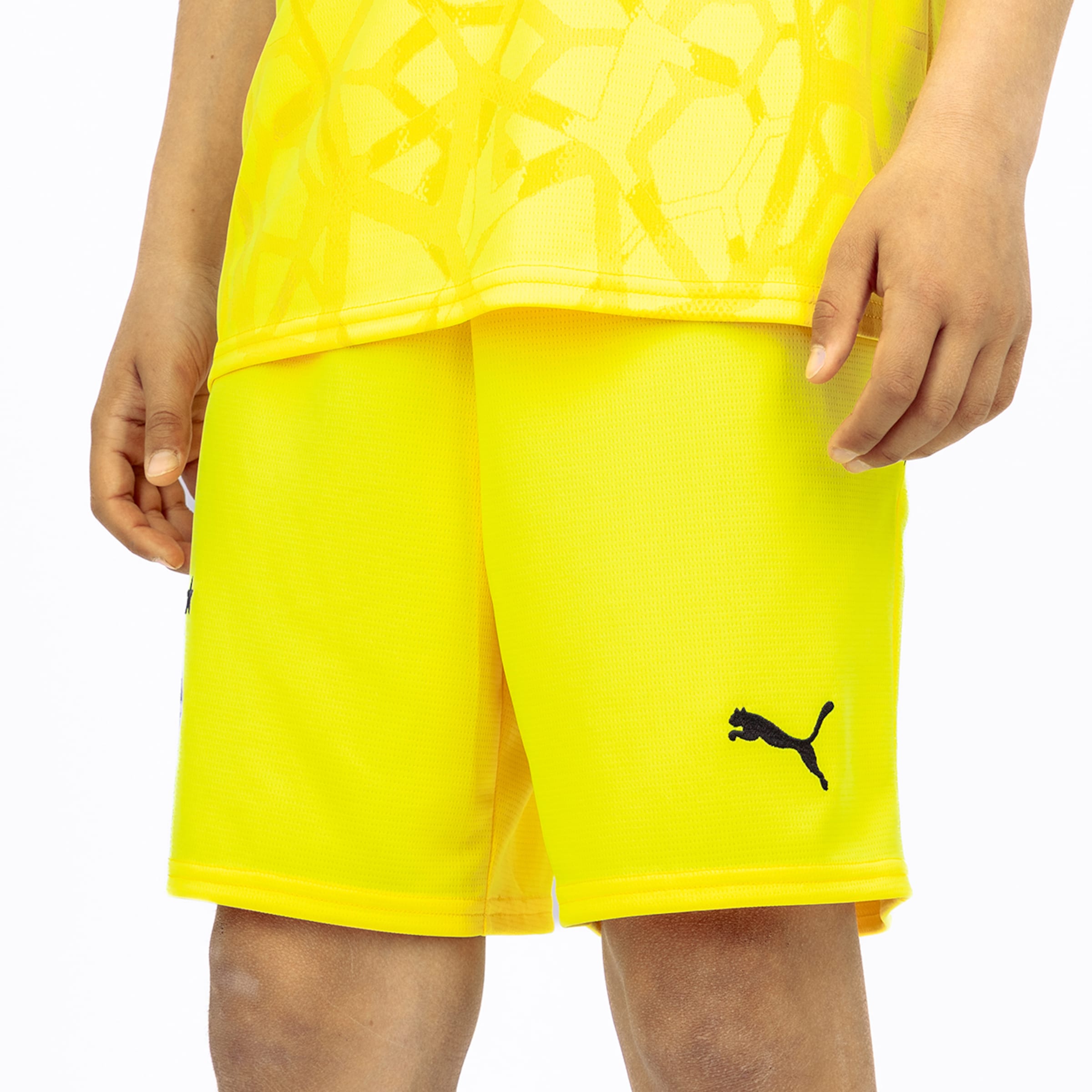 Yellow Puma sports shorts with a matching patterned jersey against a white background. Black Puma logo on the left leg.