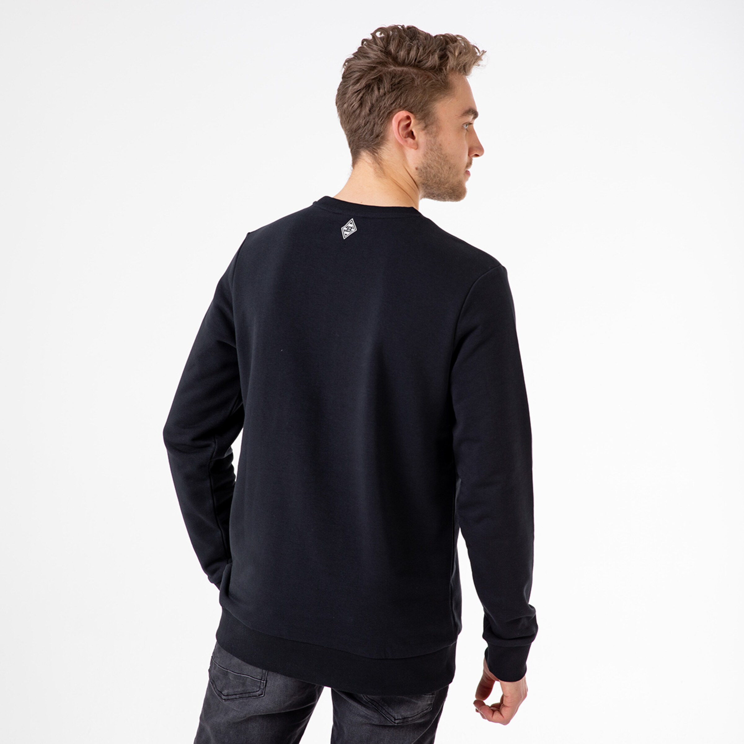 Mann trägt schwarzen Pullover mit rundem Ausschnitt und zeigt den Rücken.