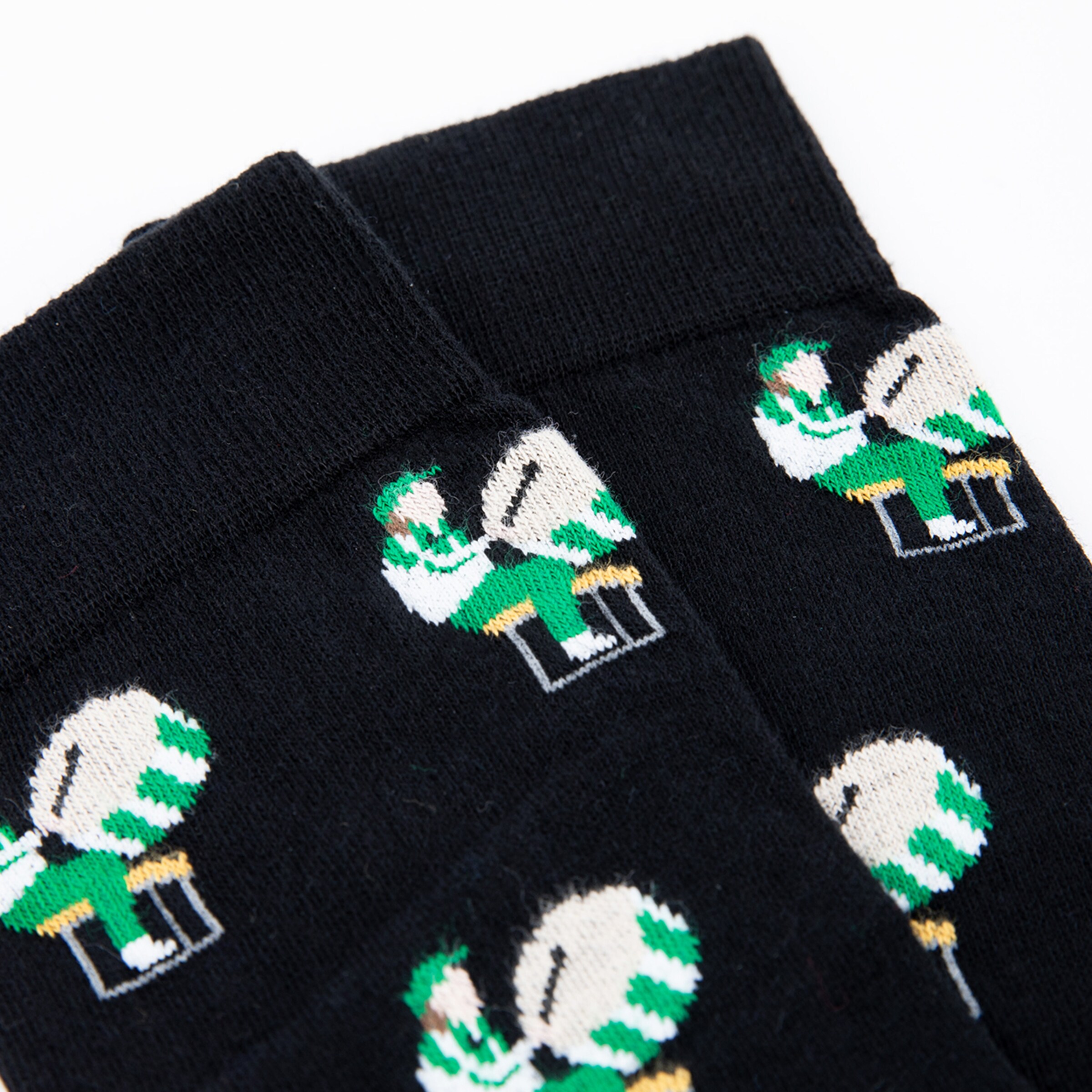 Black socks featuring green and white patterns of soccer players sitting on a ball.