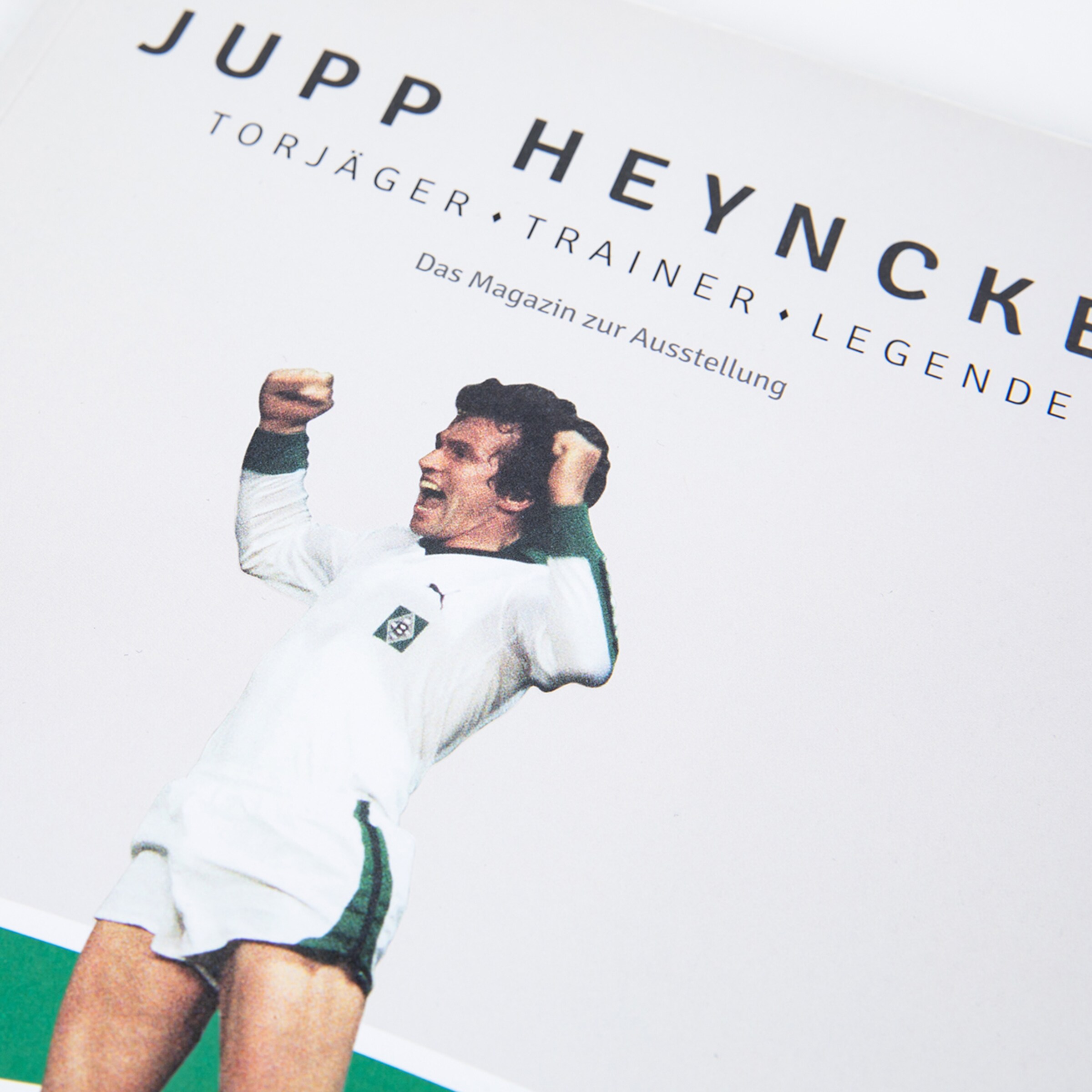 Jupp Heynckes in white kit celebrating with raised arms.