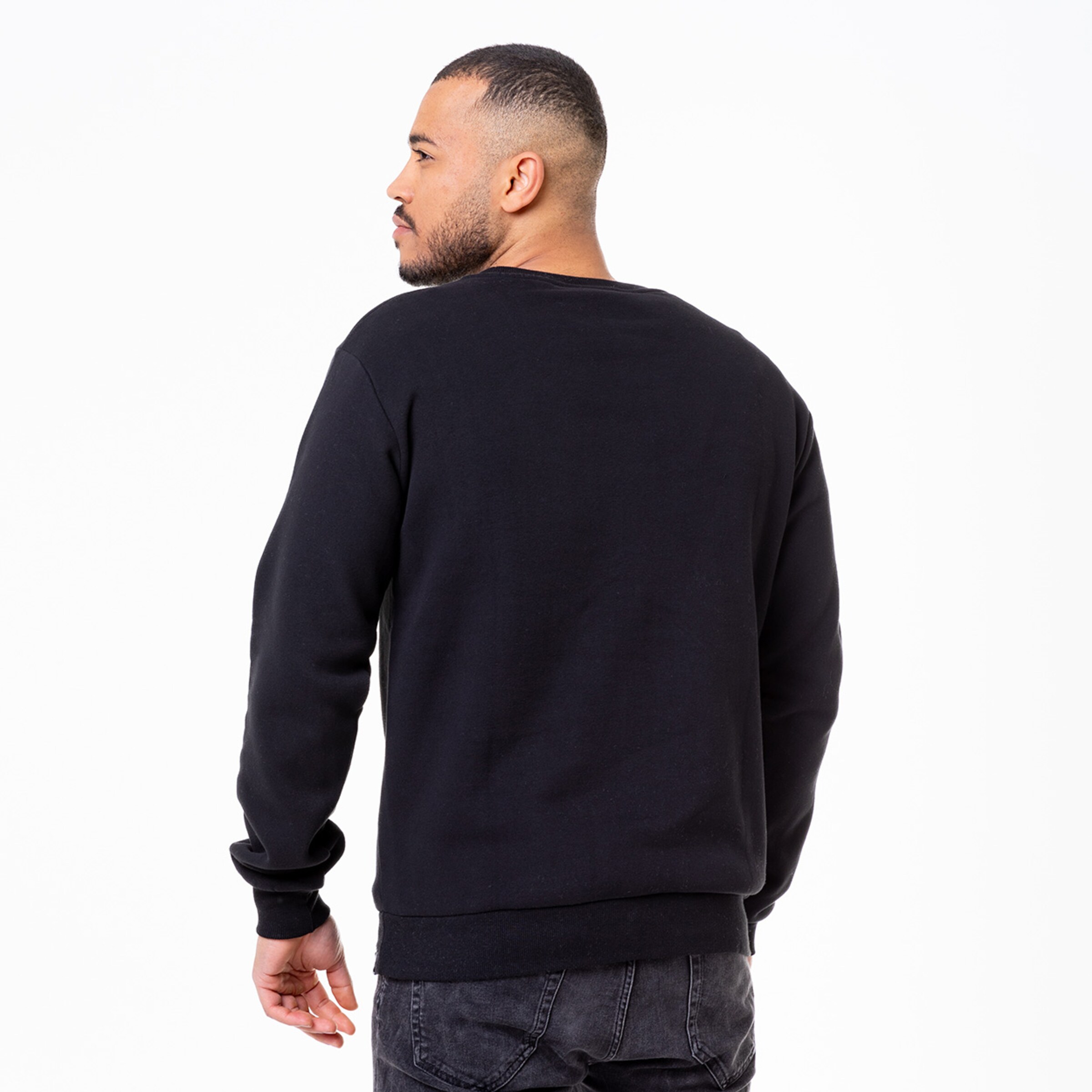 Man wearing a black sweatshirt looking over his shoulder.