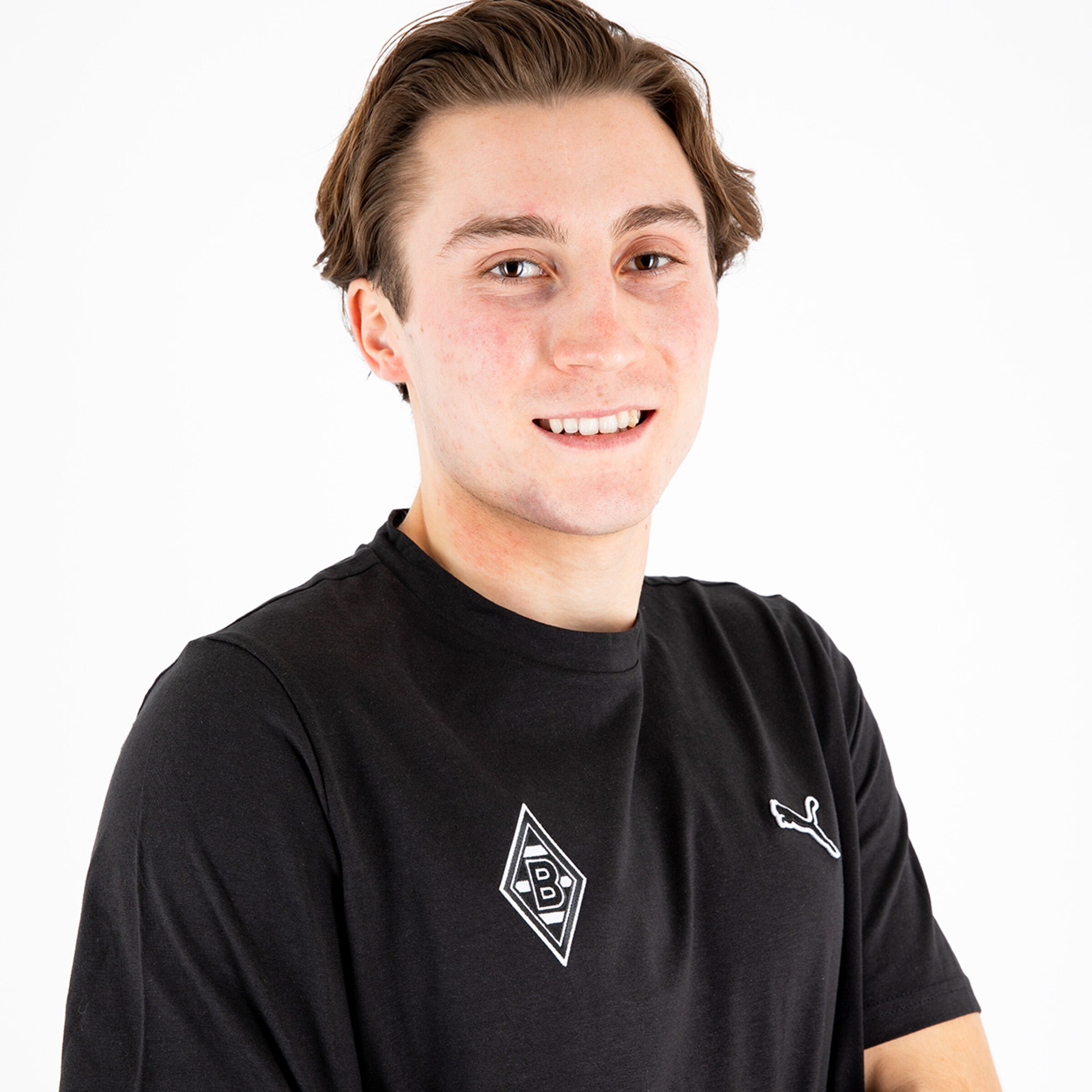 Young man with short brown hair wearing a black t-shirt featuring Borussia Mönchengladbach logo.