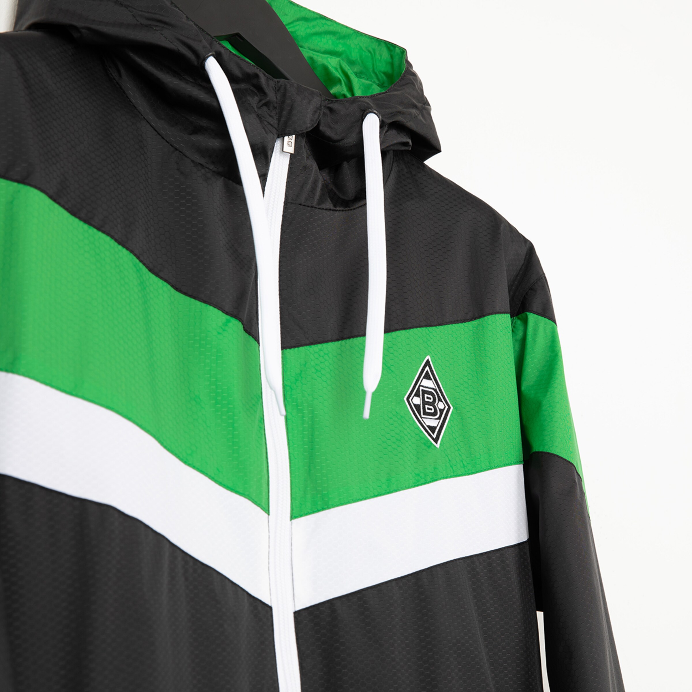Schwarz-grüne Jacke mit weißem Streifen und Borussia Mönchengladbach Logo.