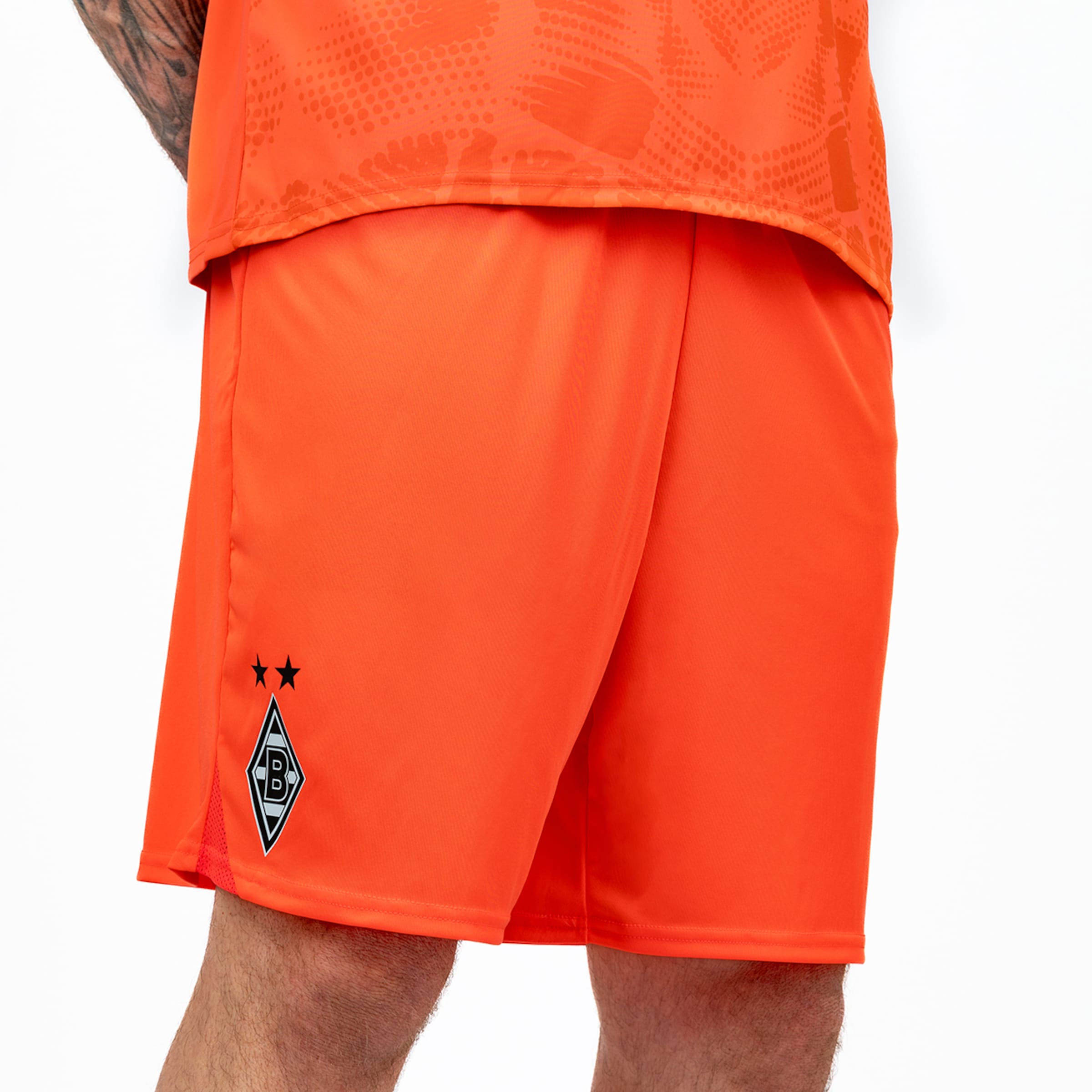 Orangefarbene Fußballshorts mit dem Vereinswappen von Borussia Mönchengladbach und zwei schwarzen Sternen.