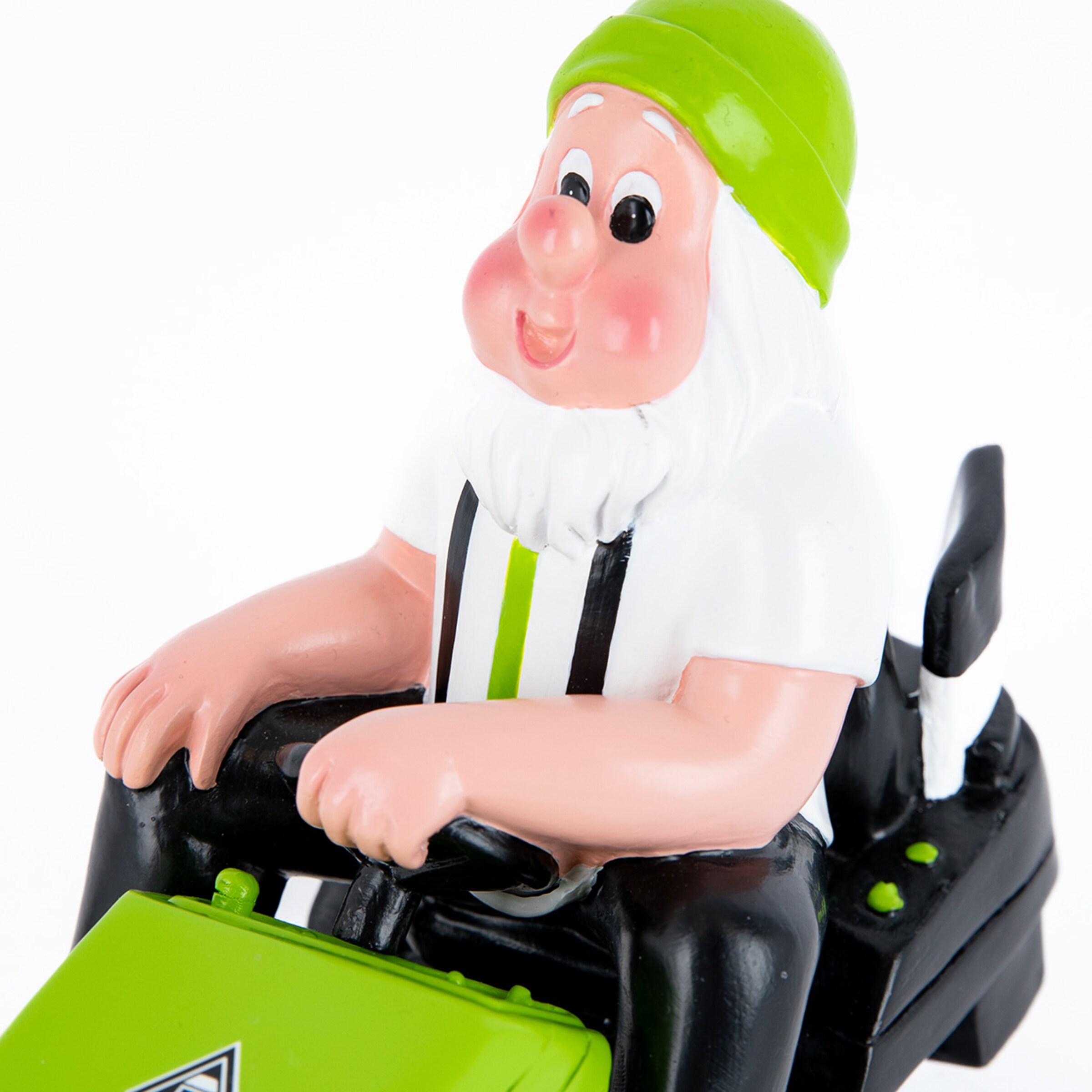 Gartenfigur eines Zwerges mit grüner Mütze auf einem grünen Rasenmäher vor weißem Hintergrund.