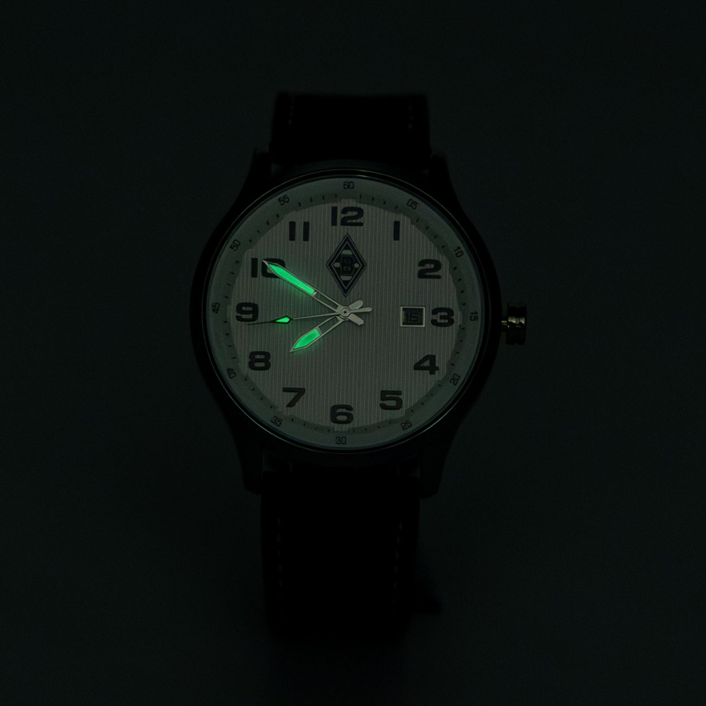 Borussia Mönchengladbach Armbanduhr im Dunkeln mit weißem Zifferblatt, schwarzen Ziffern und grün leuchtenden Zeigern.