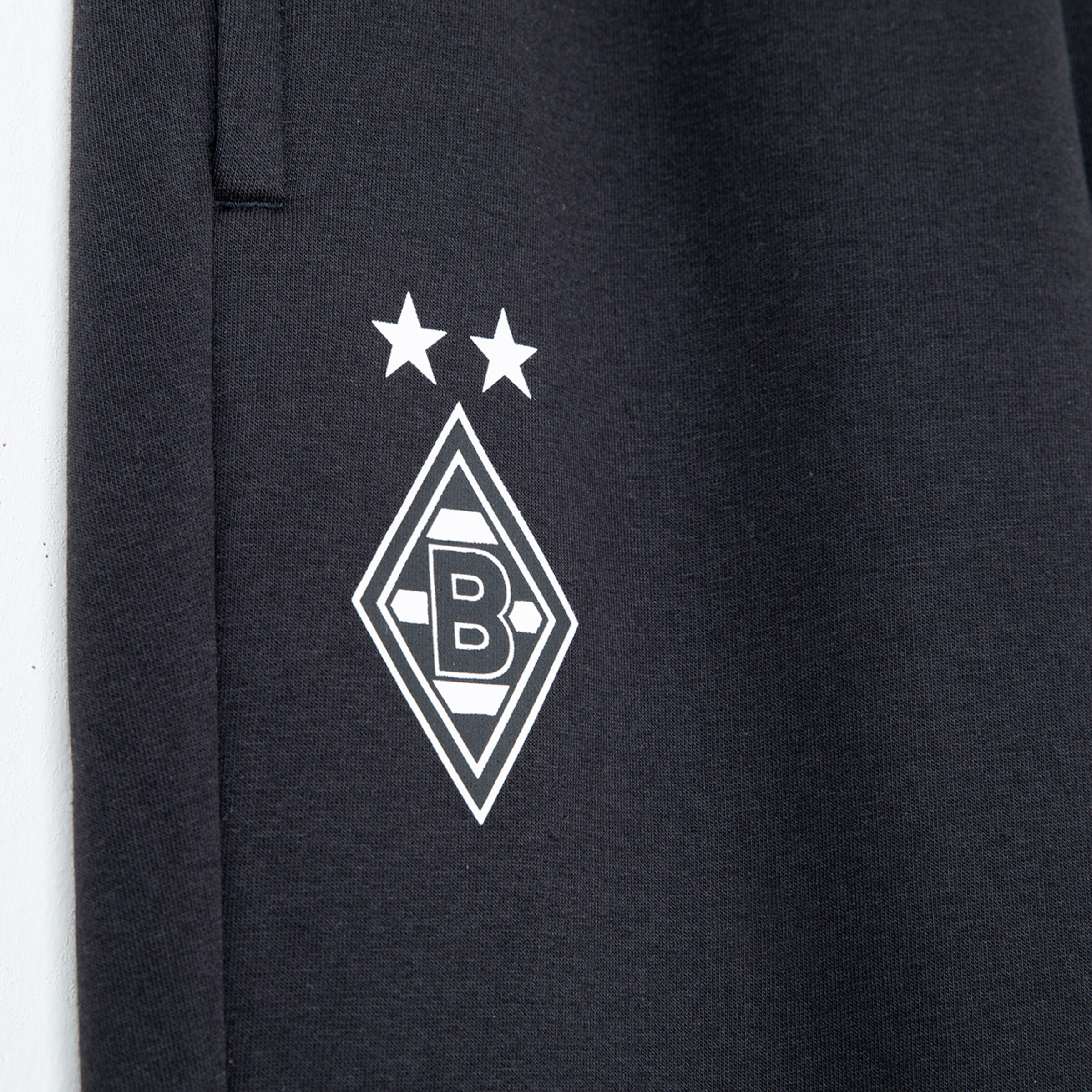 Logo von Borussia Mönchengladbach mit zwei Sternen auf dunkelblauer Sporthose.