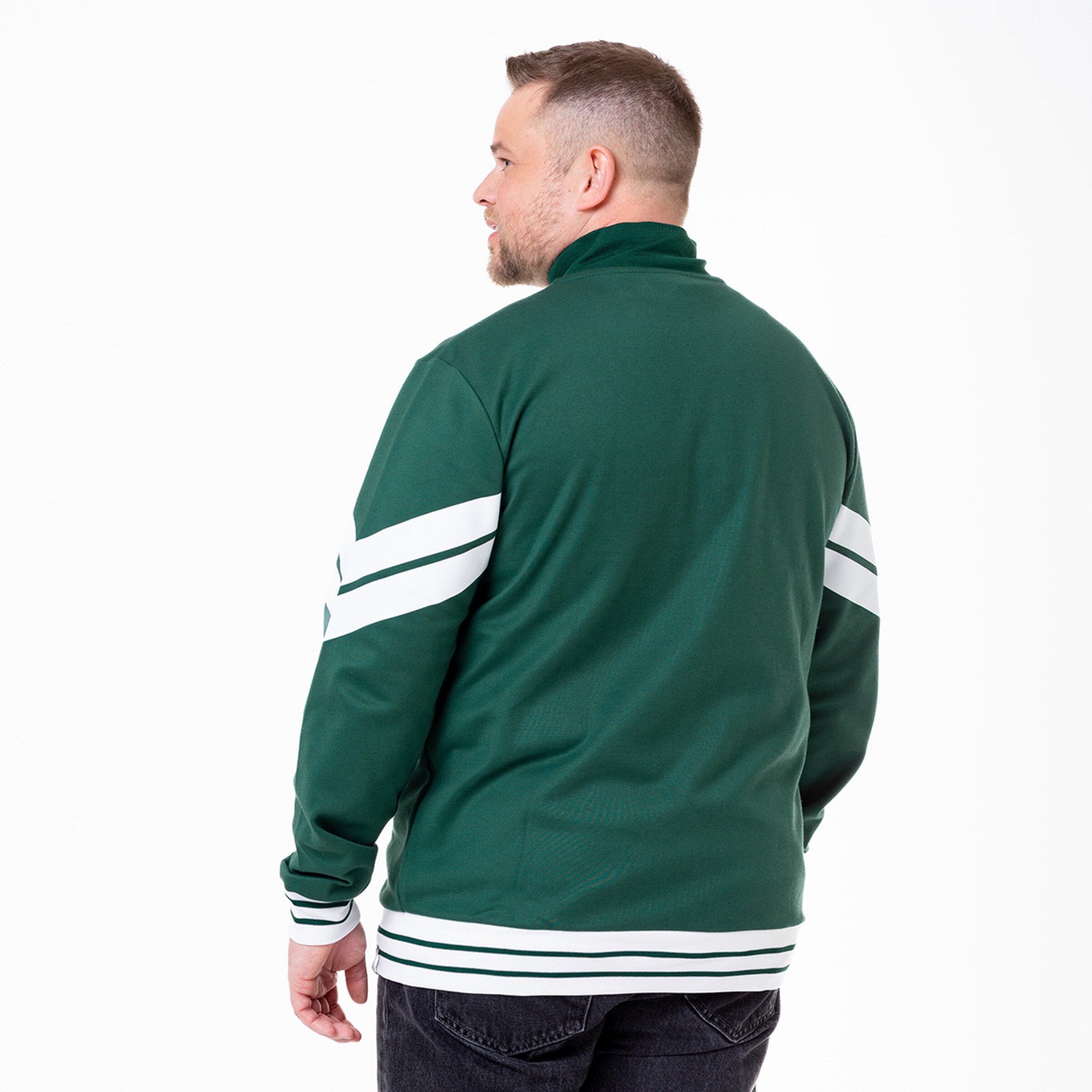 Mann mit kurz gescheiteltem Haar trägt eine grüne Jacke mit weißen Streifen auf den Ärmeln.