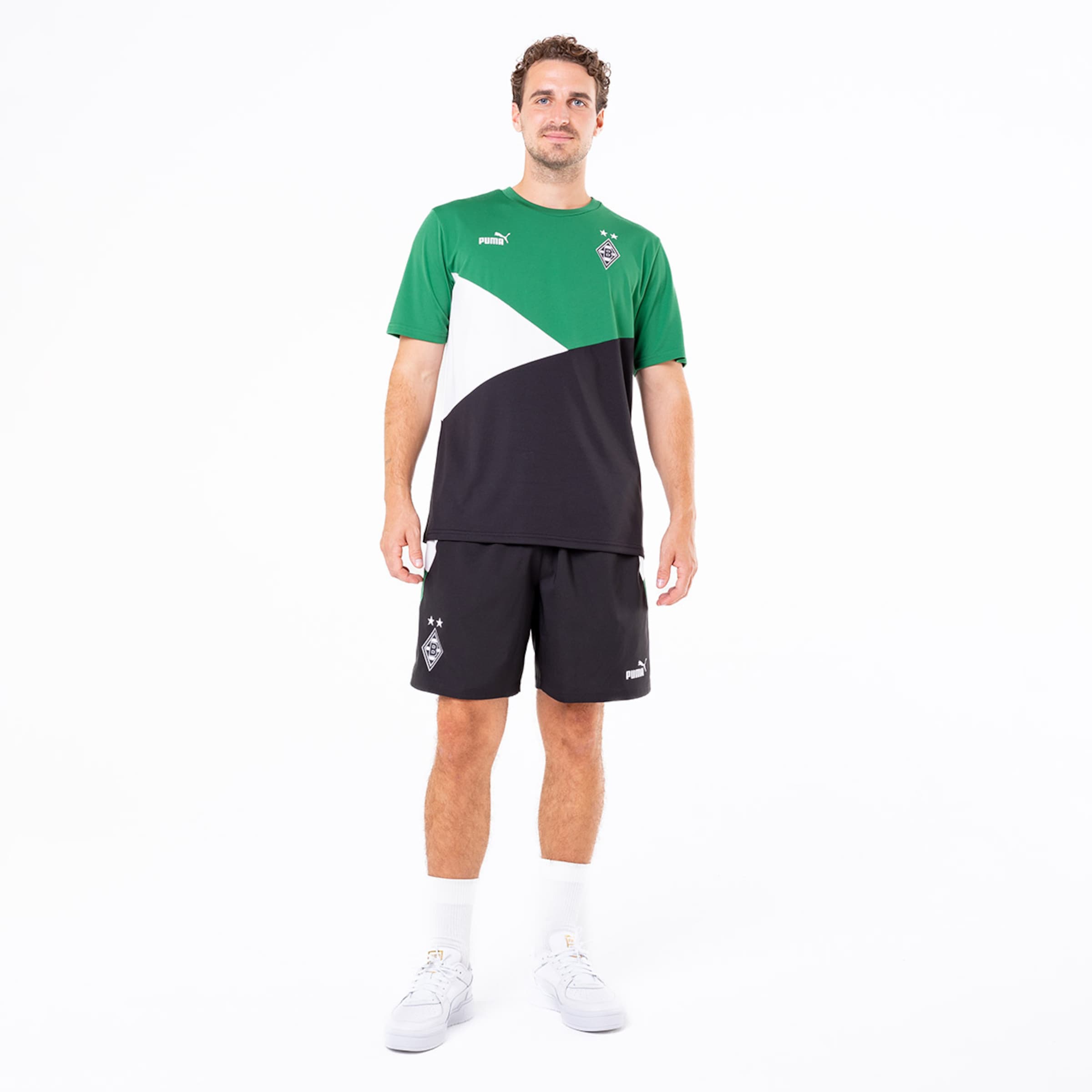 Sportler trägt Trikot und Shorts mit grünen und schwarzen Farben von Puma.