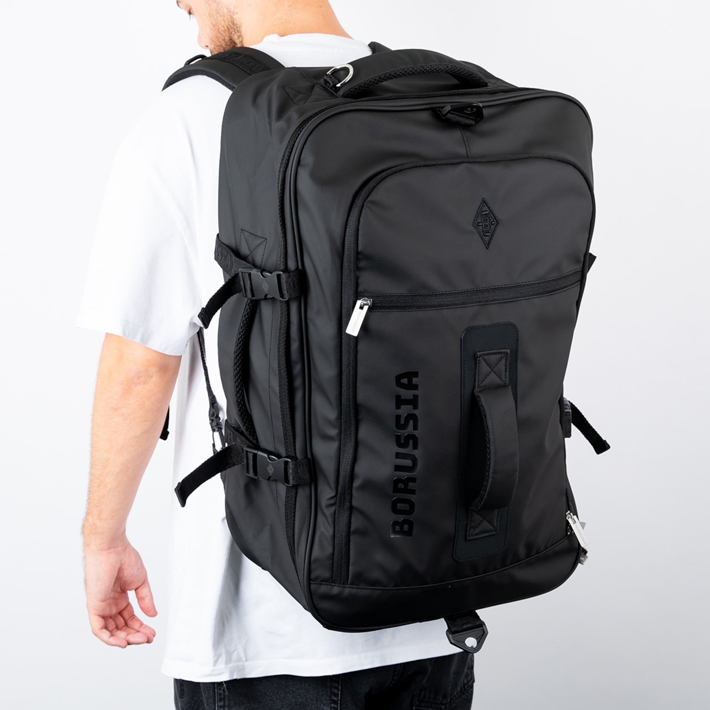 Schwarzer Rucksack mit dem Aufdruck BORUSSIA auf der Vorderseite getragen von einem Mann im Hintergrund.