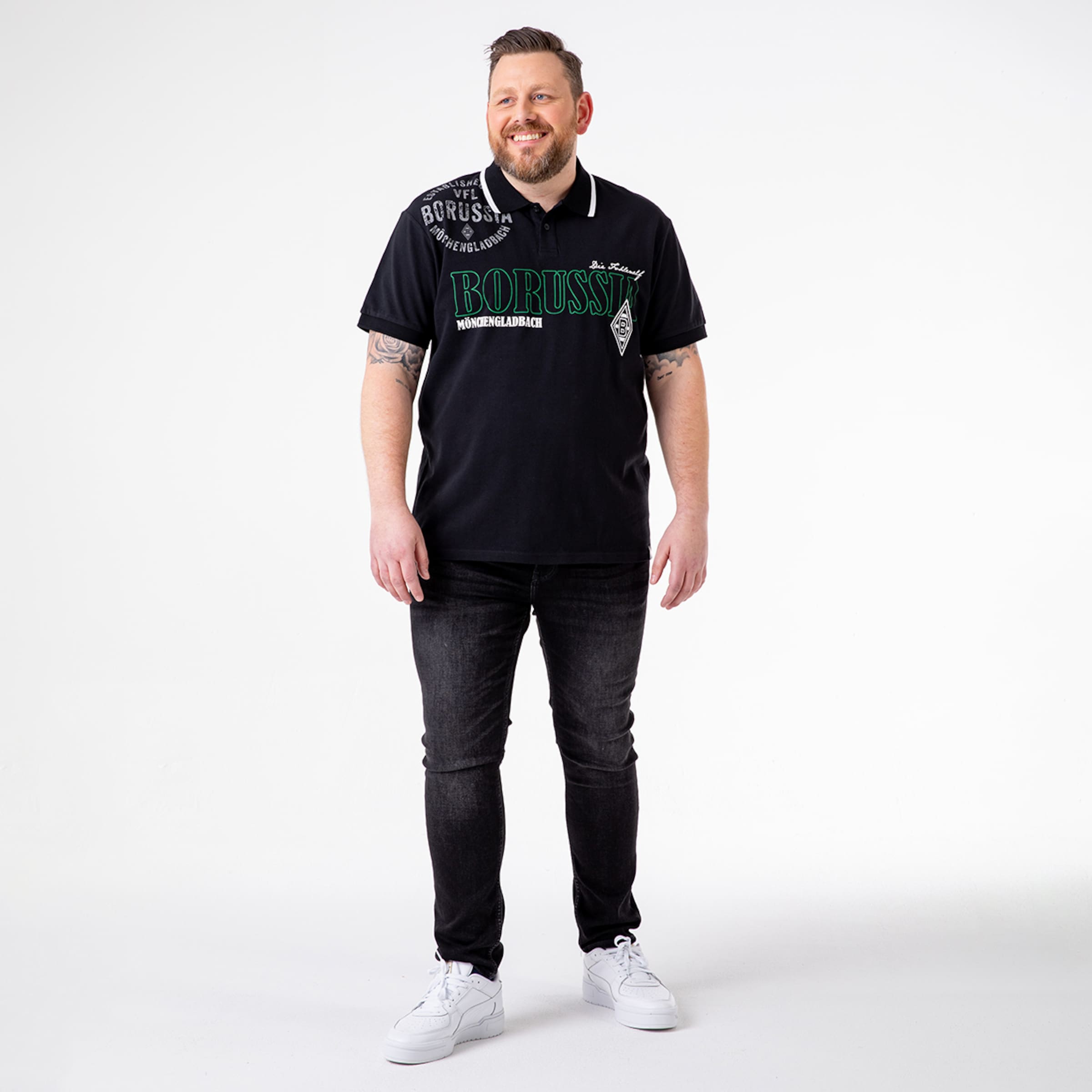 Man wearing a black polo shirt with Borussia Mönchengladbach logo and jeans.