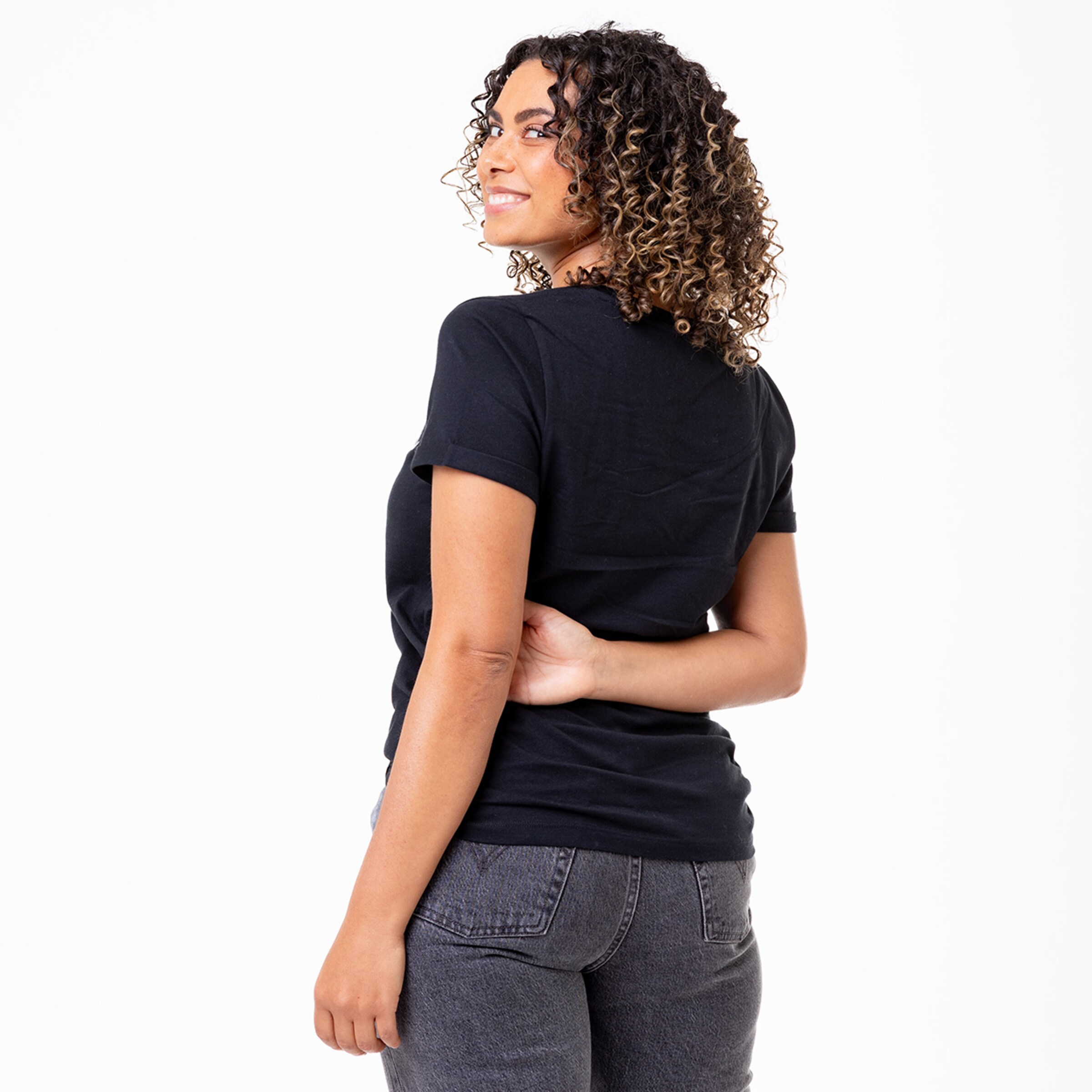 Woman with curly hair turned away from the camera wearing a black t-shirt and jeans.