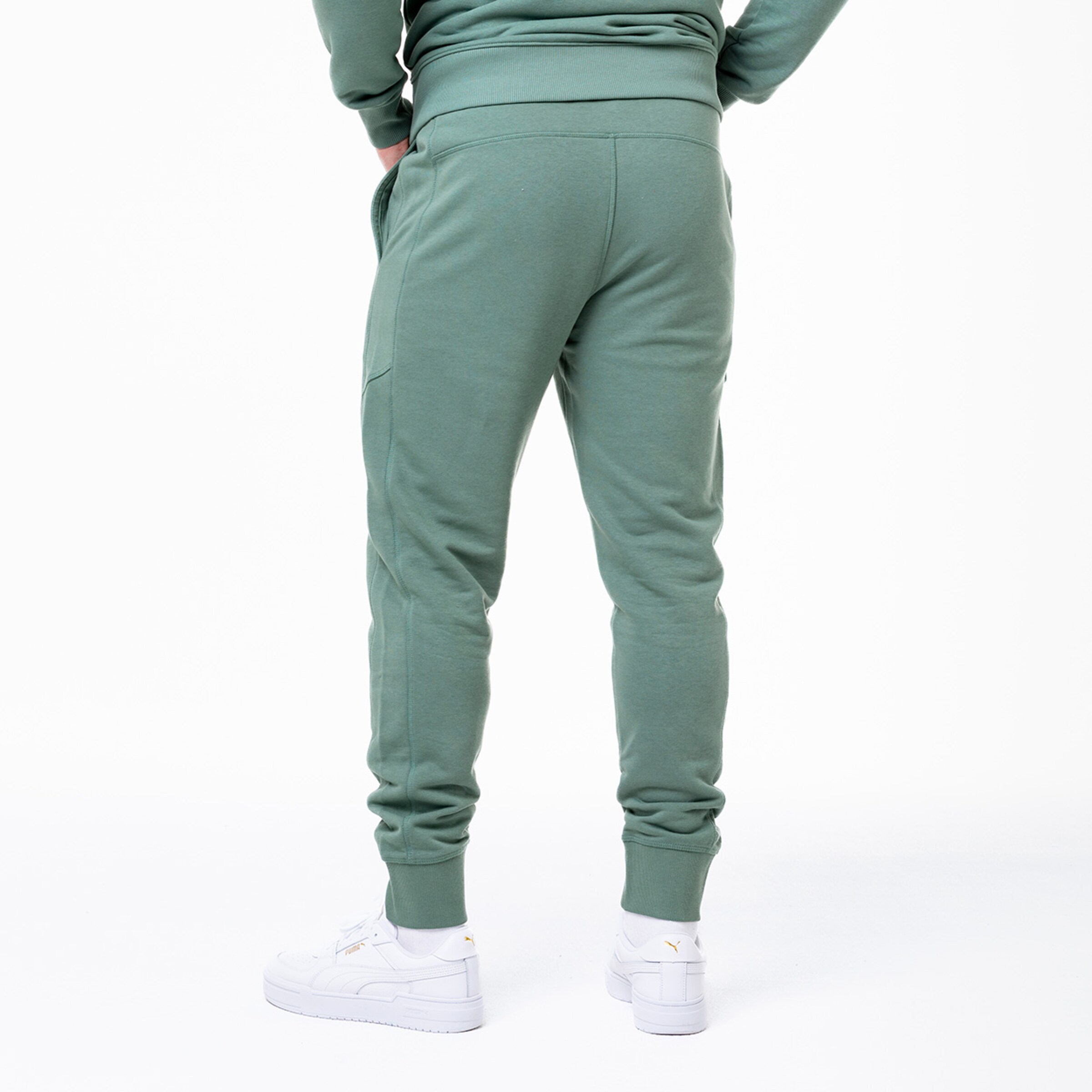 Mann mit grünem Jogginganzug von hinten weiße Schuhe sichtbar.