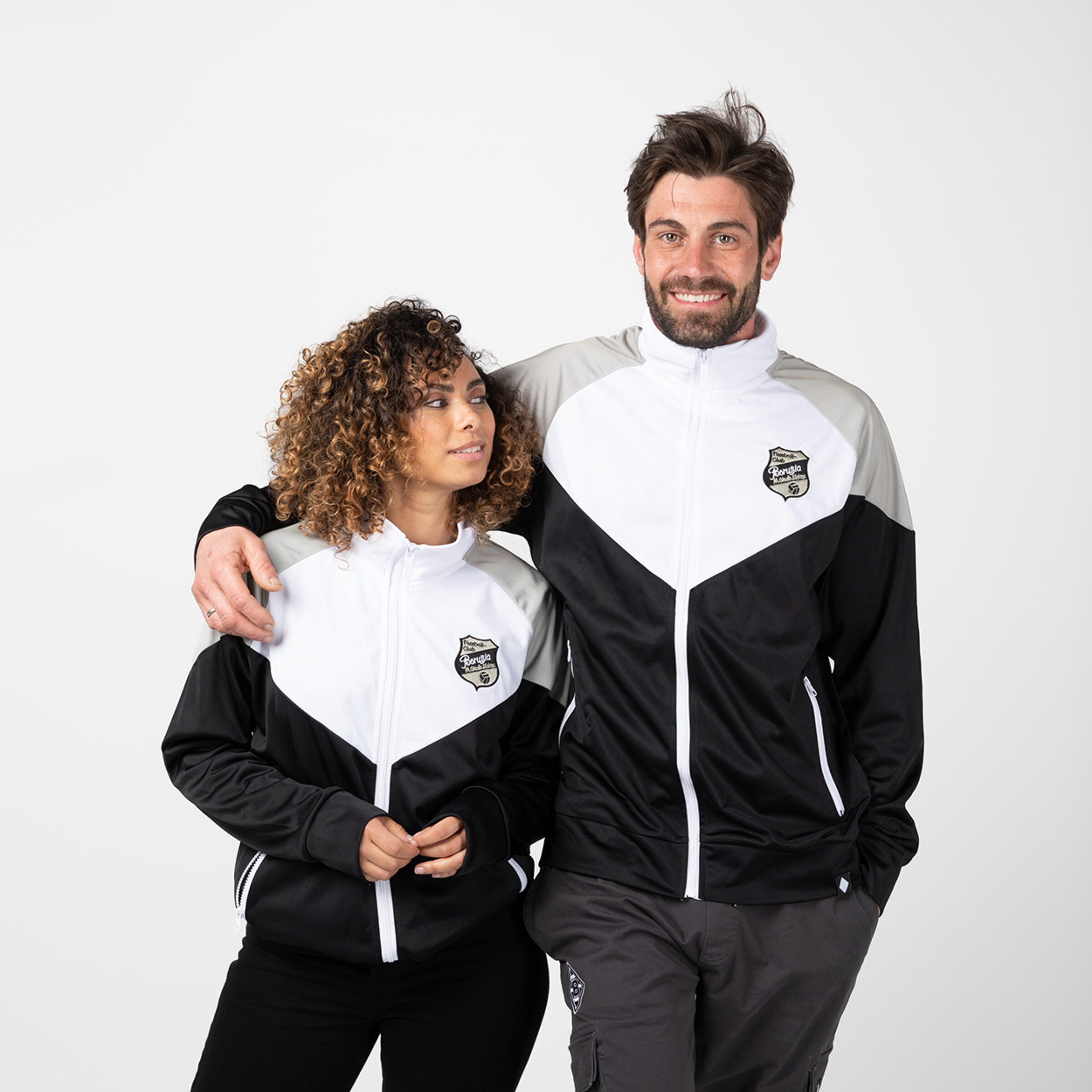 Zwei Personen tragen schwarze und weiße Sportjacken mit dem Borussia Mönchengladbach Logo.